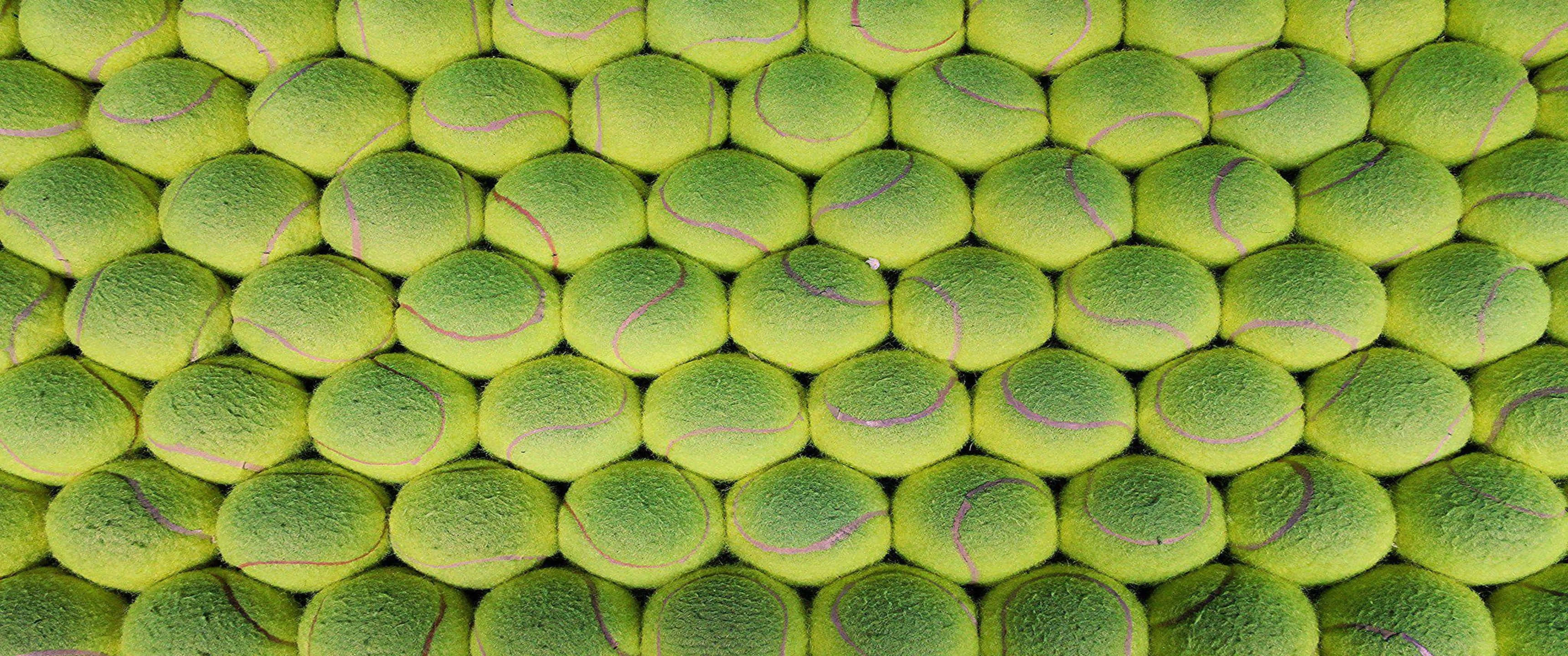 3440x1440p Tennis 桌布 壁紙 — 鮮黃色網球以褪色紫色縫線緊密排列成行的密集圖案。