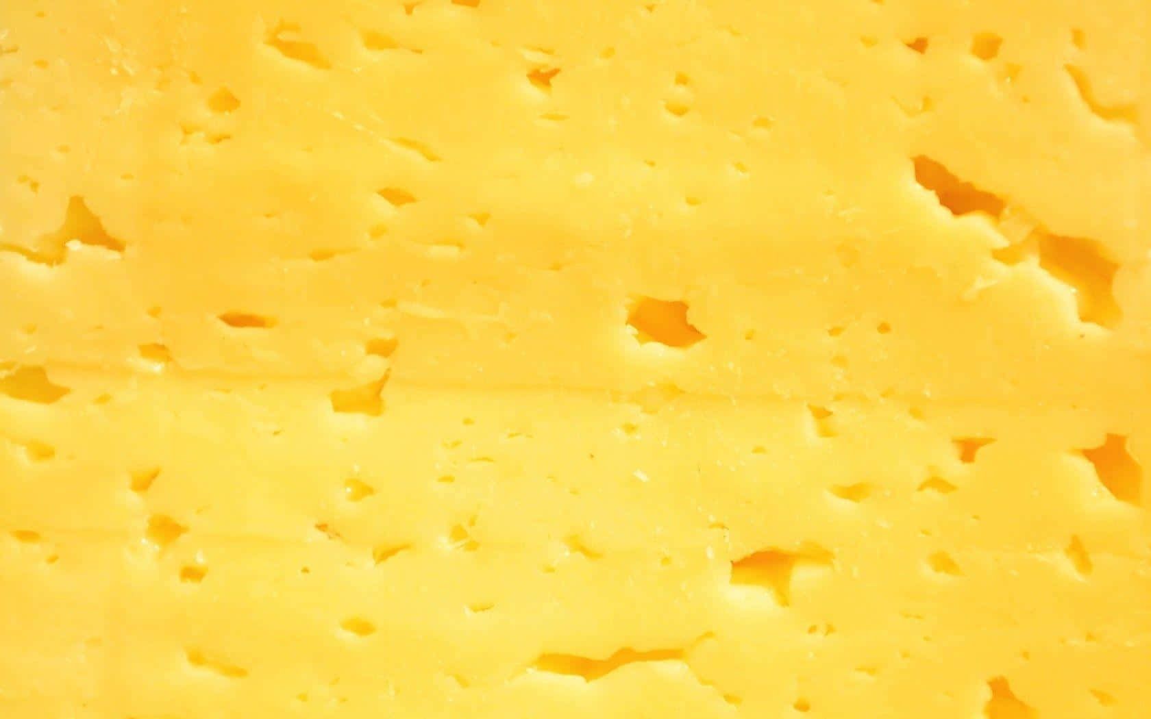 Cheese 桌布 壁紙 — 鮮黃色起司的近距離特寫，帶有不規則孔洞和光滑質地。