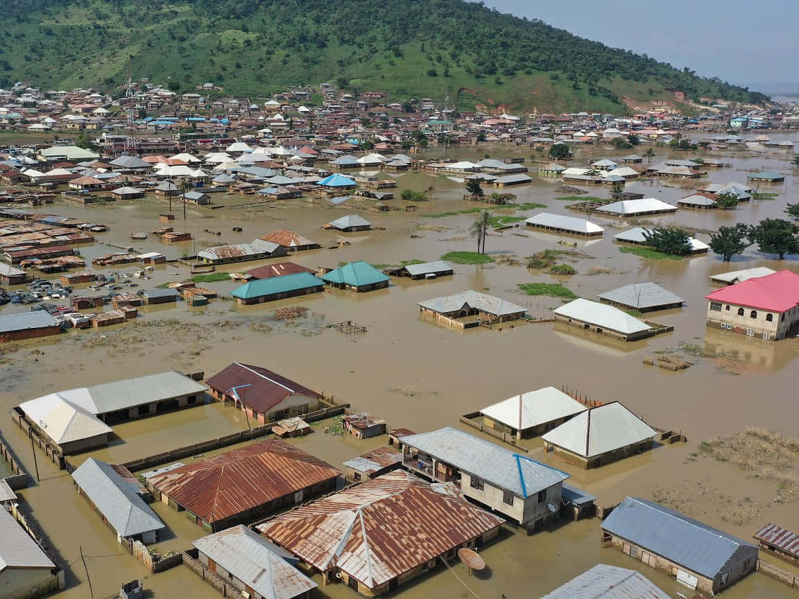 Flood 桌布 壁紙 — 鳥瞰一個被洪水淹沒的城鎮，泥水淹沒房屋和街道，天空晴朗。