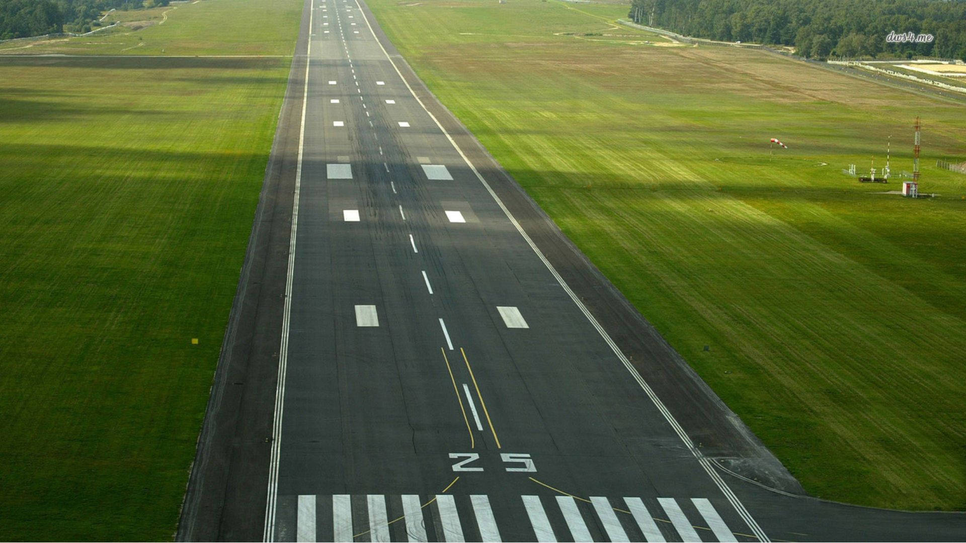 Runway 桌布 壁紙 — 鳥瞰一條長長的機場跑道，兩旁是鮮綠色的田野，在明亮的日光下。