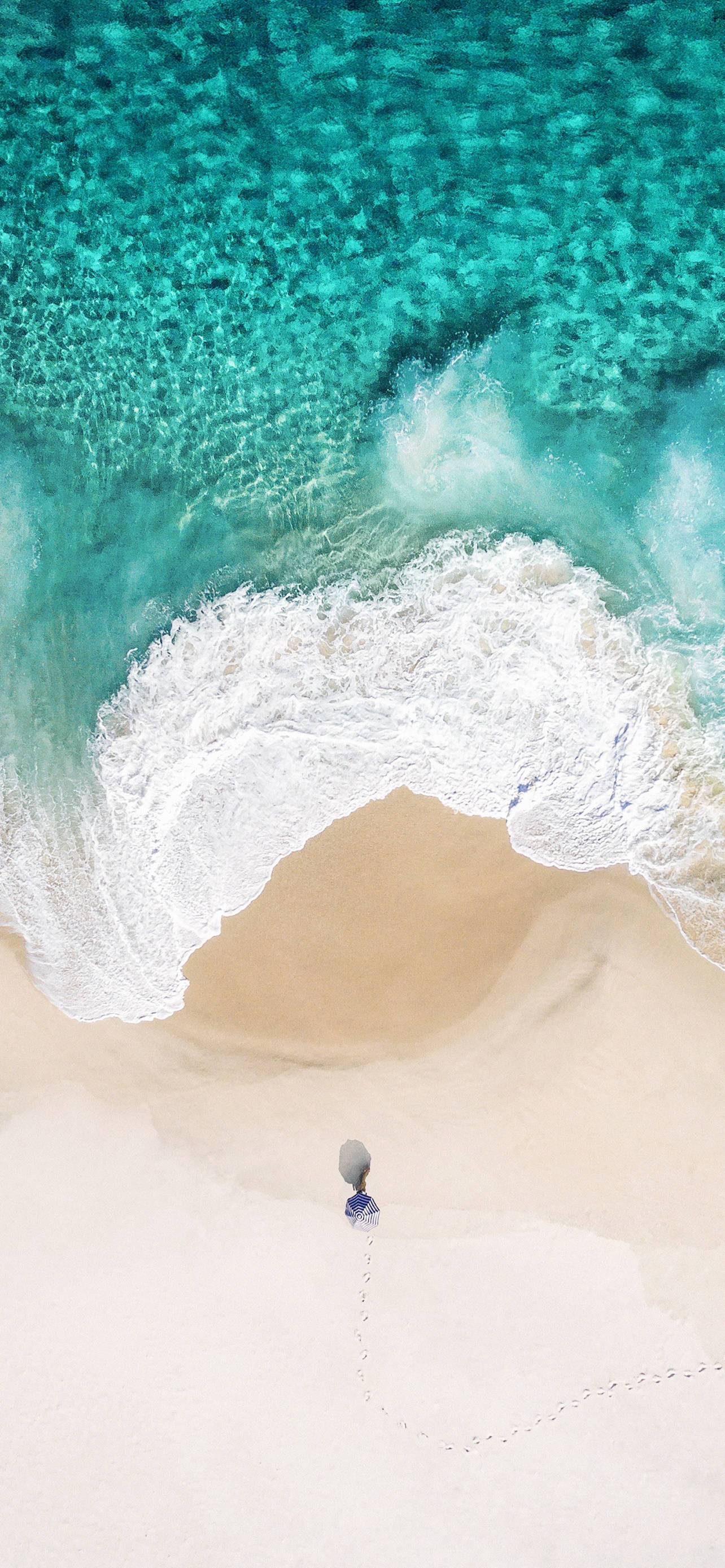 iPhone X Beach 桌布 壁紙 — 鳥瞰圖：一個人獨自走在純白沙灘上，走向碧綠的海浪。