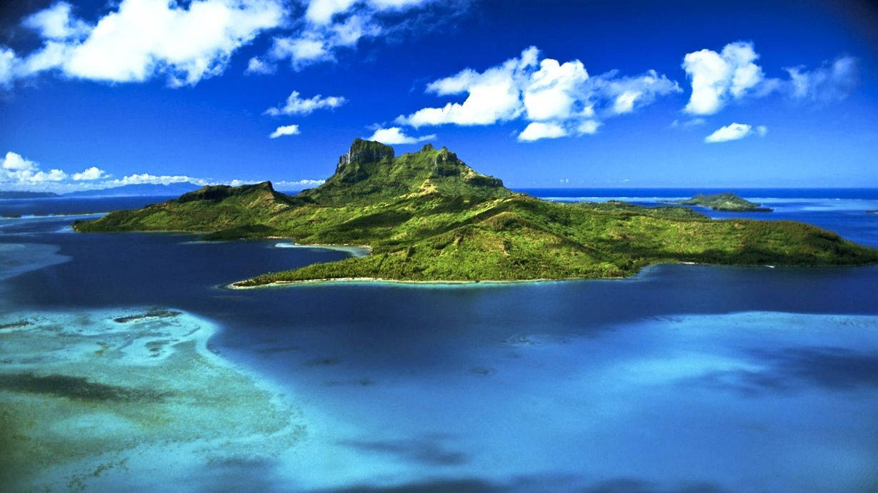 Mauritius 桌布 壁紙 — 鳥瞰圖：一個鬱鬱蔥蔥的綠色島嶼，擁有火山峰，被碧綠的潟湖和深藍色的海洋環繞，天空明亮，白雲朵朵。