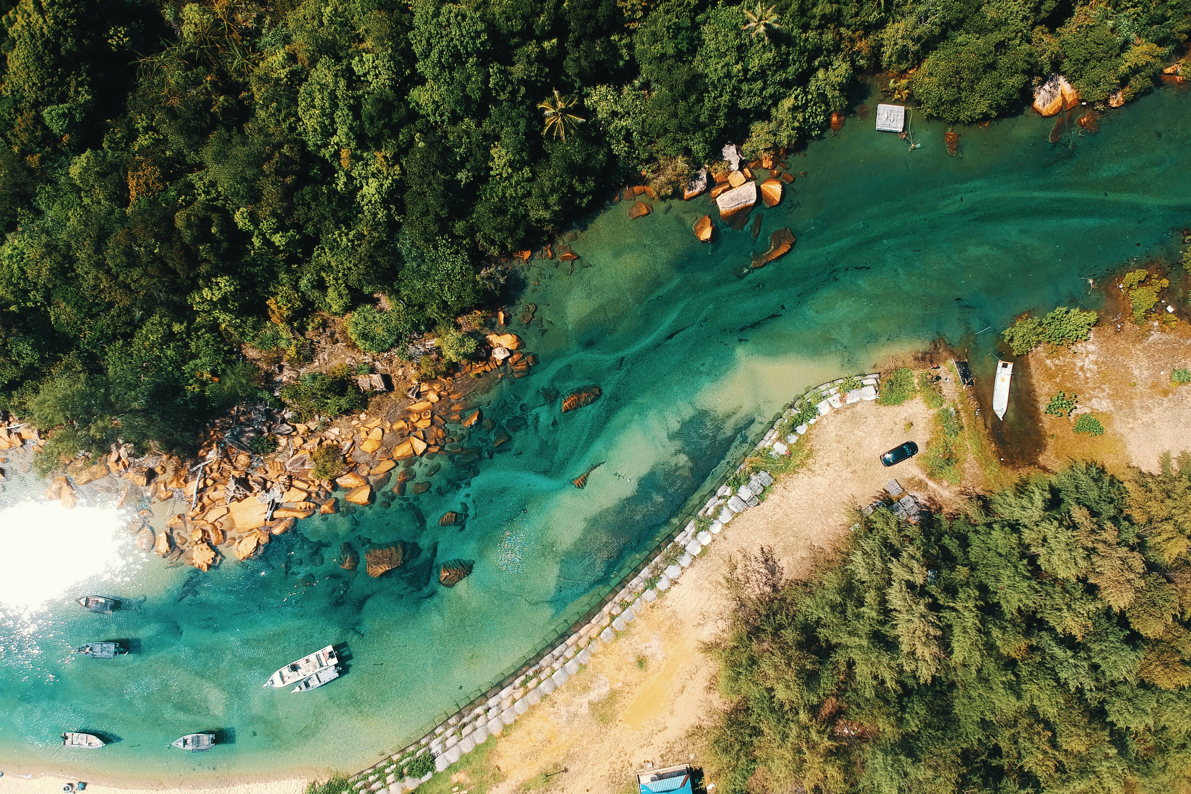river 桌布 壁紙 — 鳥瞰圖，碧綠海水擁抱著沙灘海灣，兩旁是茂密的綠色叢林和散落的船隻。