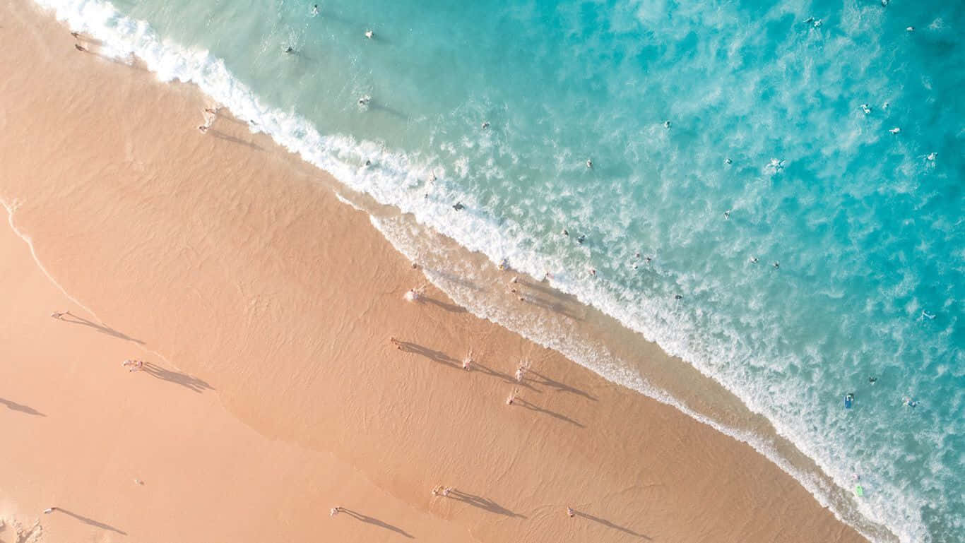 HD Beach 桌布 壁紙 — 鳥瞰圖：碧綠海浪拍打金色沙灘，零星遊客享受陽光。