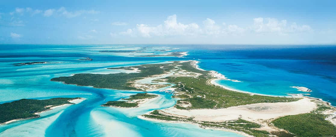 Bahamas Island 桌布 壁紙 — 鳥瞰圖：碧綠潟湖蜿蜒於翠綠島嶼之間，天空湛藍，白雲點綴。