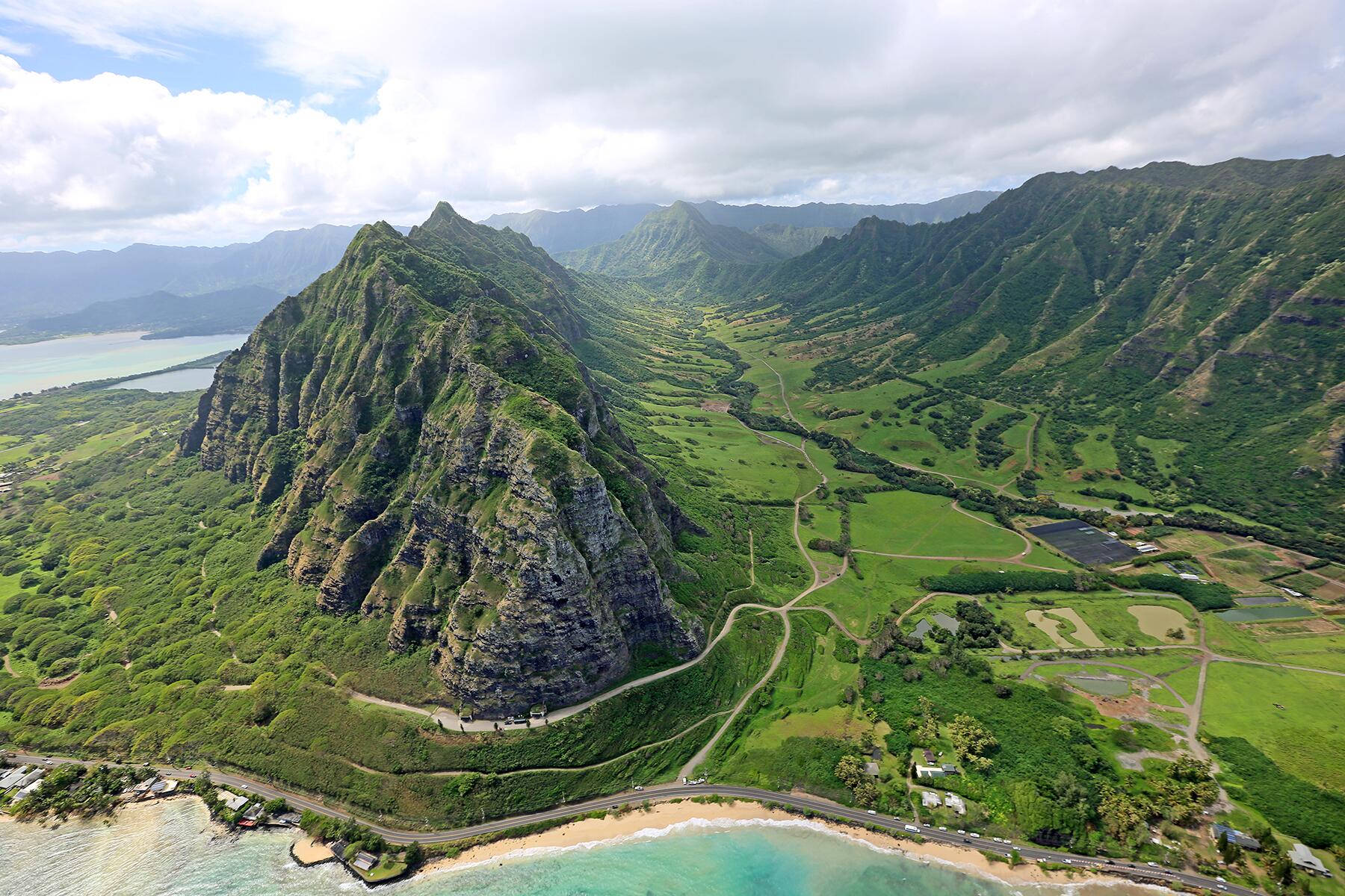 風景 桌布 壁紙 — 鳥瞰圖：鬱鬱蔥蔥的青山落入碧綠的海洋，蜿蜒的道路和沿海村莊在陰天之下。