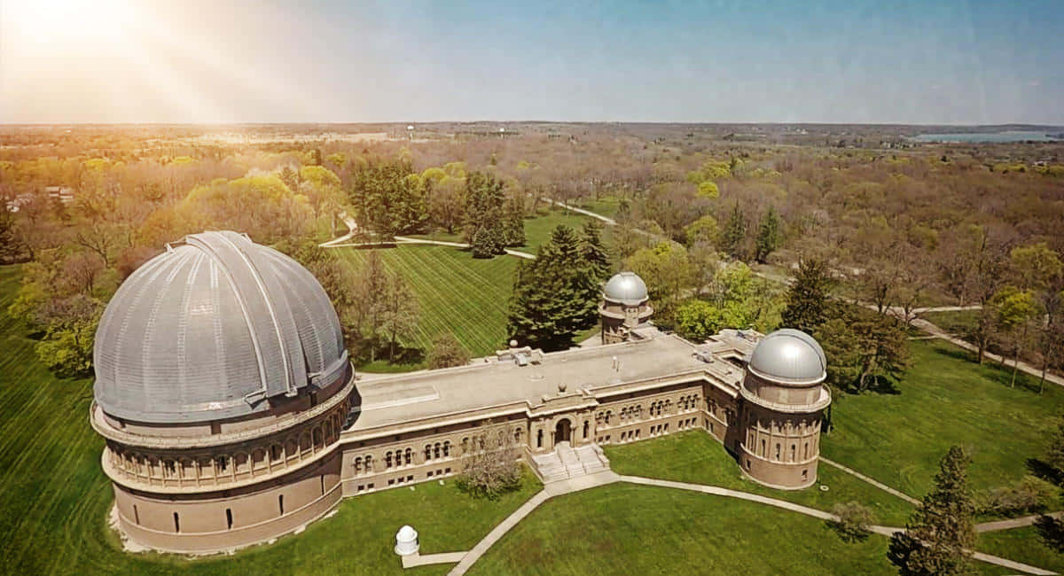 Observatory 桌布 壁紙 — 鳥瞰圖顯示一個宏偉的天文台，擁有三個圓頂，坐落在陽光明媚的翠綠景觀中。
