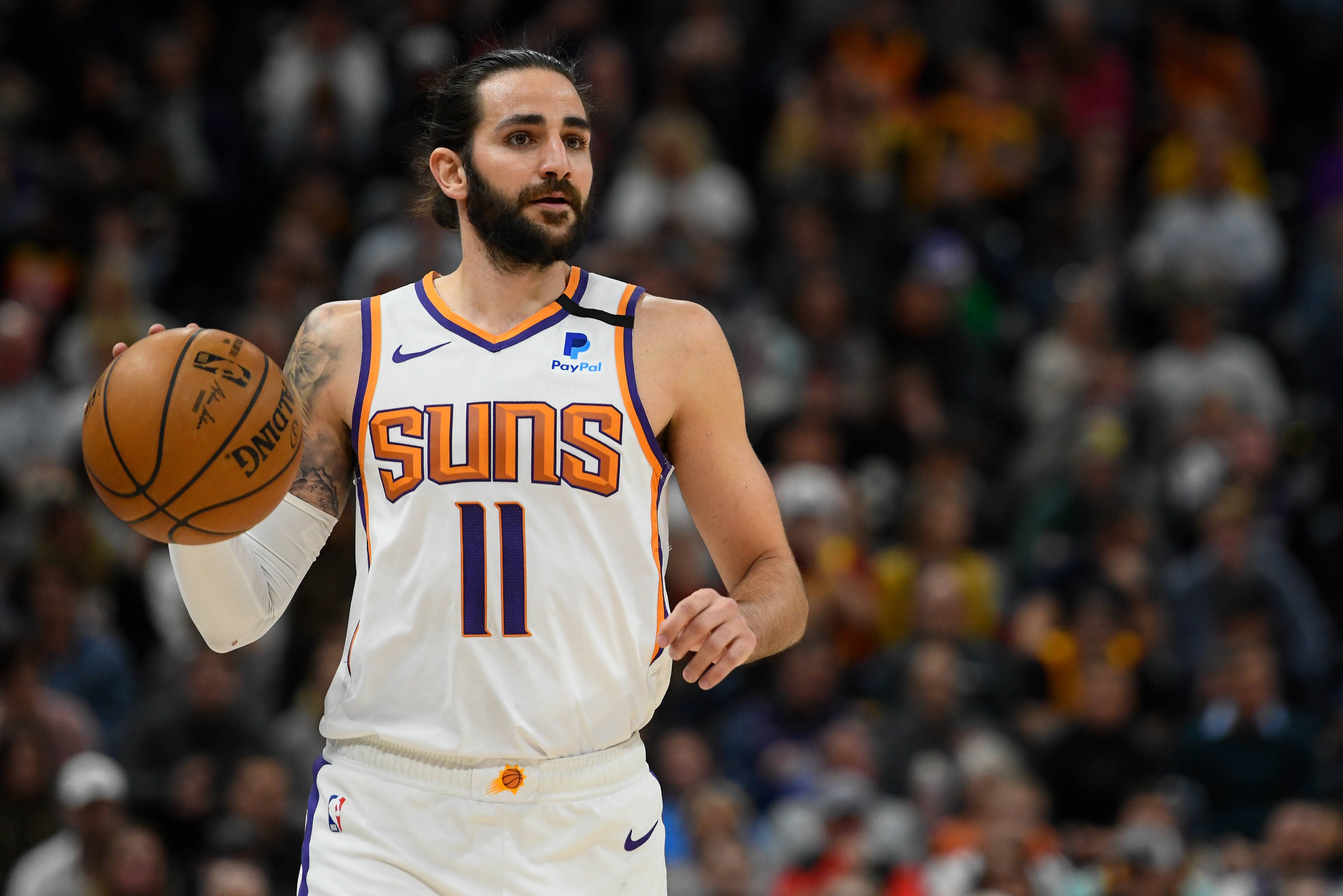 Ricky Rubio 桌布 壁紙 — 鳳凰城太陽隊身穿白色11號球衣的籃球運動員在比賽中運球，背景是模糊的人群。