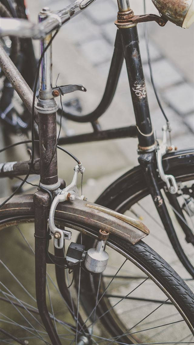 Bicycle 桌布 壁紙 — 鵝卵石街道上復古自行車前輪和把手特寫，顯示生鏽的金屬和磨損的零件。