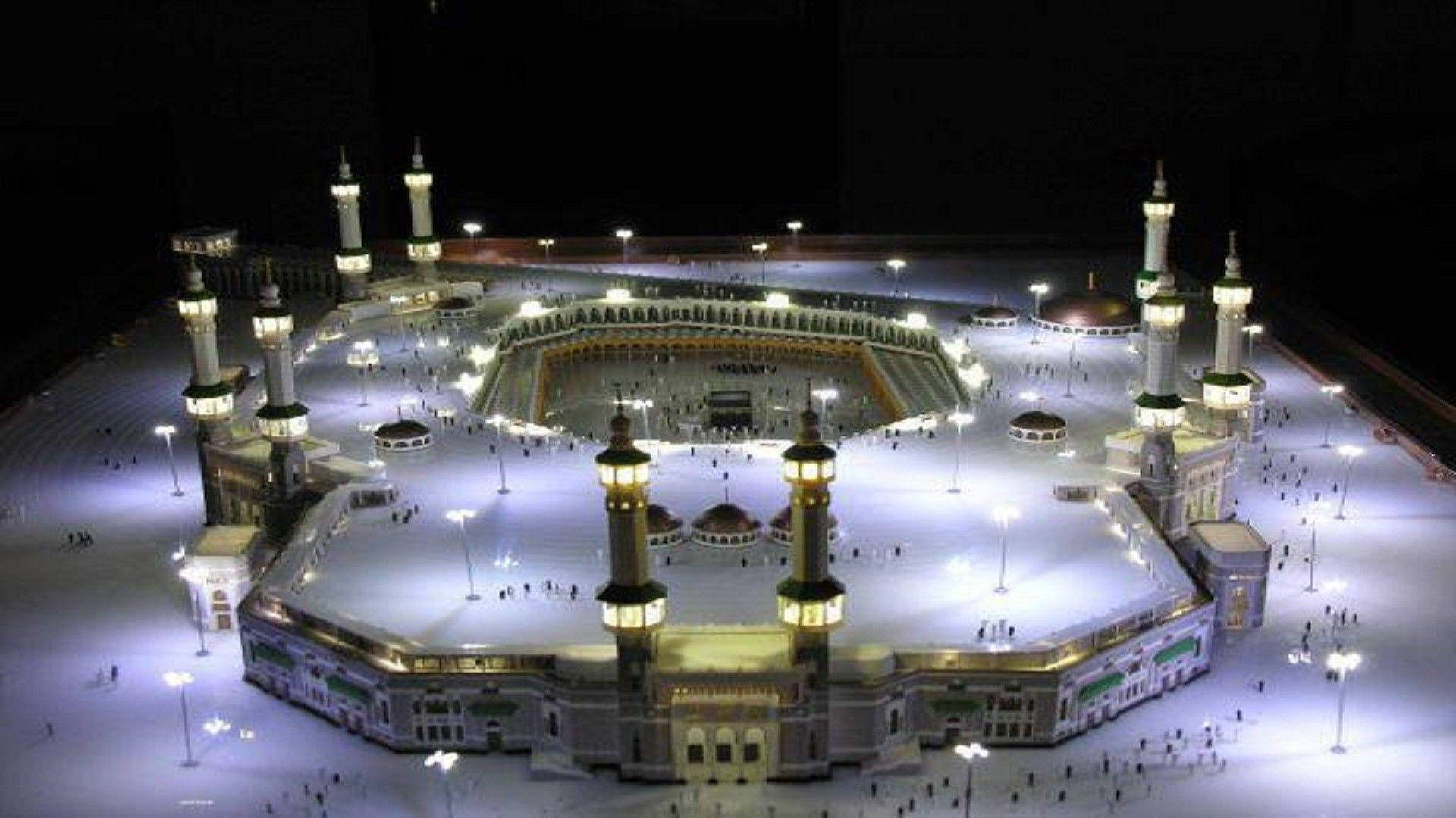 Makkah 桌布 壁紙 — 麥加 illuminated 大清真寺的夜間航拍圖，閃爍的宣禮塔和圍繞卡巴天房朝聖的信徒。