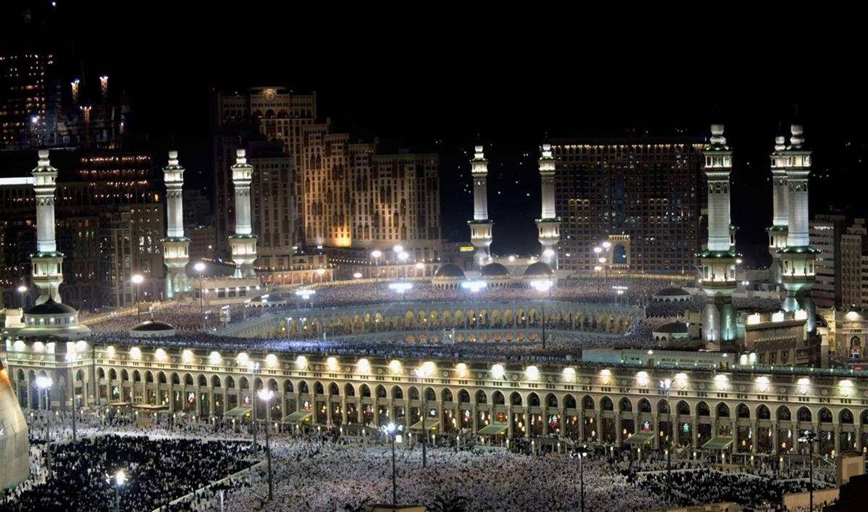 muslim 桌布 壁紙 — 麥加大清真寺的夜間鳥瞰圖，金色燈光照亮，數百萬朝聖者聚集祈禱。