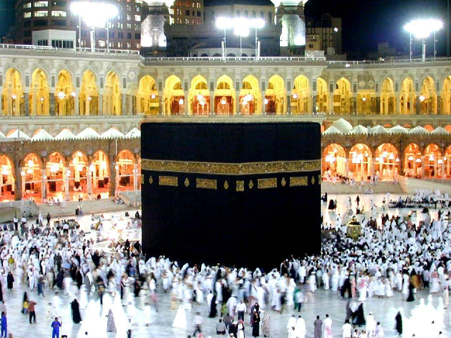 Makkah 桌布 壁紙 — 麥加天房的夜景，數千名身穿白衣的朝聖者在明亮的泛光燈下繞行。