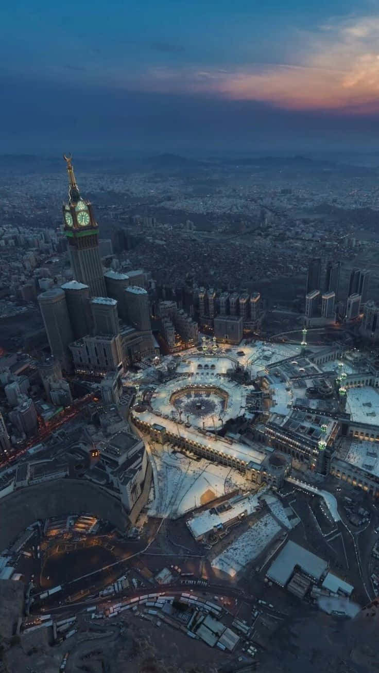 Mecca Kaaba 桌布 壁紙 — 麥加阿布拉吉阿爾拜特鐘樓和麥加大清真寺在黃昏時的鳥瞰圖，下方城市燈光閃爍。