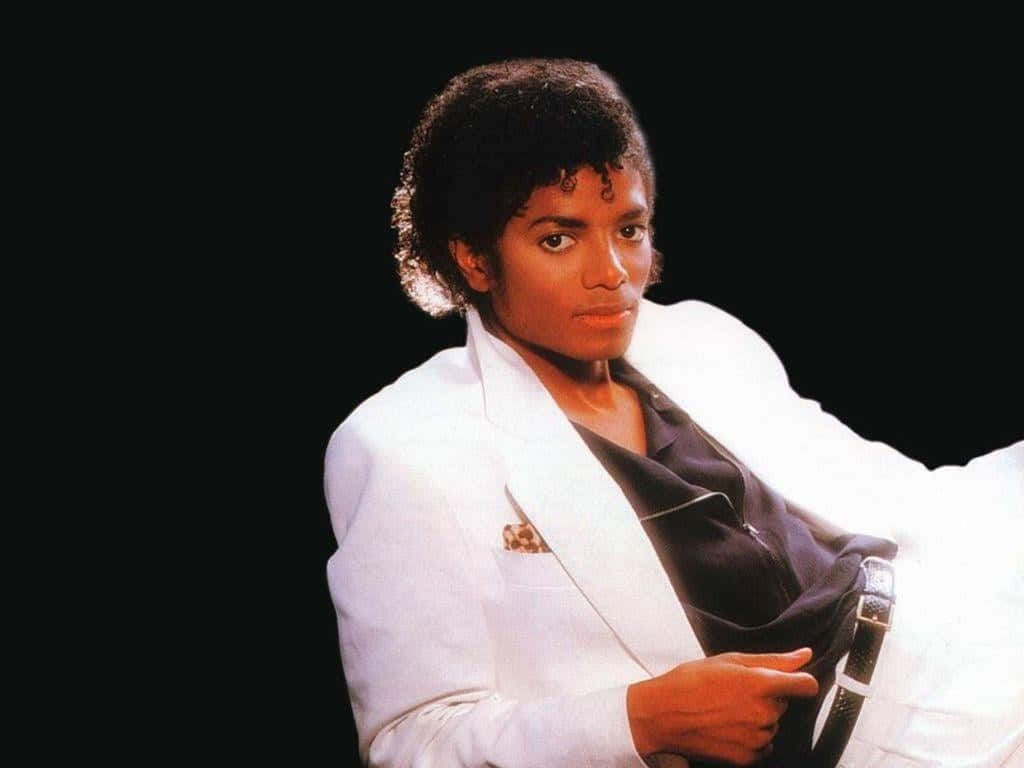 Michael Jackson Thriller 桌布 壁紙 — 麥可傑克森身穿白色西裝，在黑色背景前自信地擺姿勢，燈光效果戲劇性。