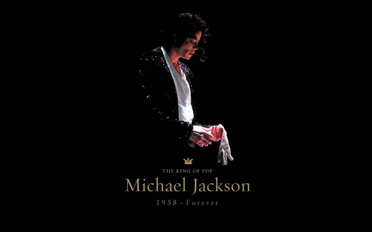michael 桌布 壁紙 — 麥可傑克森身穿閃亮黑色外套和白色手套，在黑色背景上照亮，下方有文字。