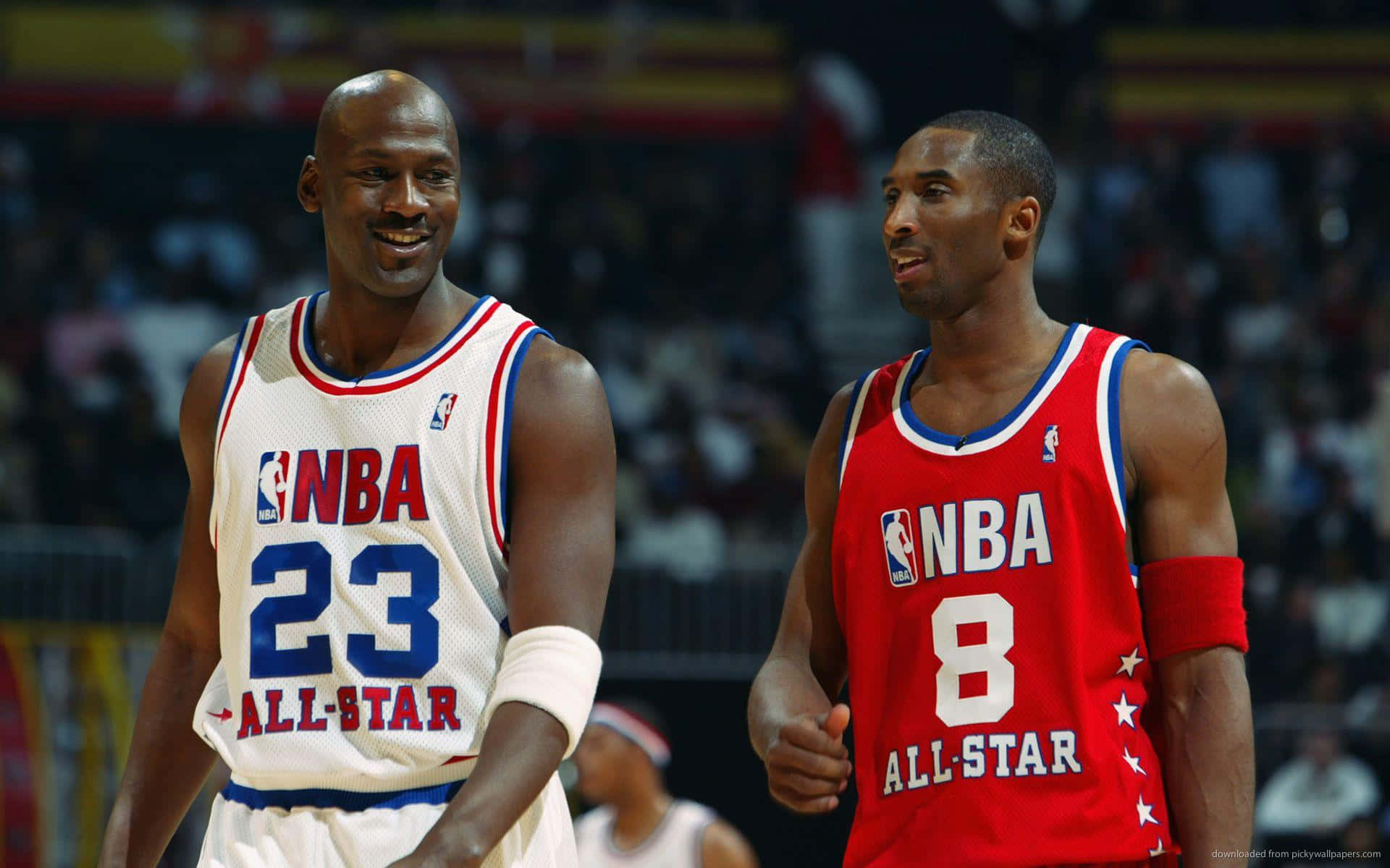 Jordan And Kobe 桌布 壁紙 — 麥可喬丹和柯比布萊恩在NBA全明星球衣中微笑並一起行走，在明亮的場館燈光下進行比賽。