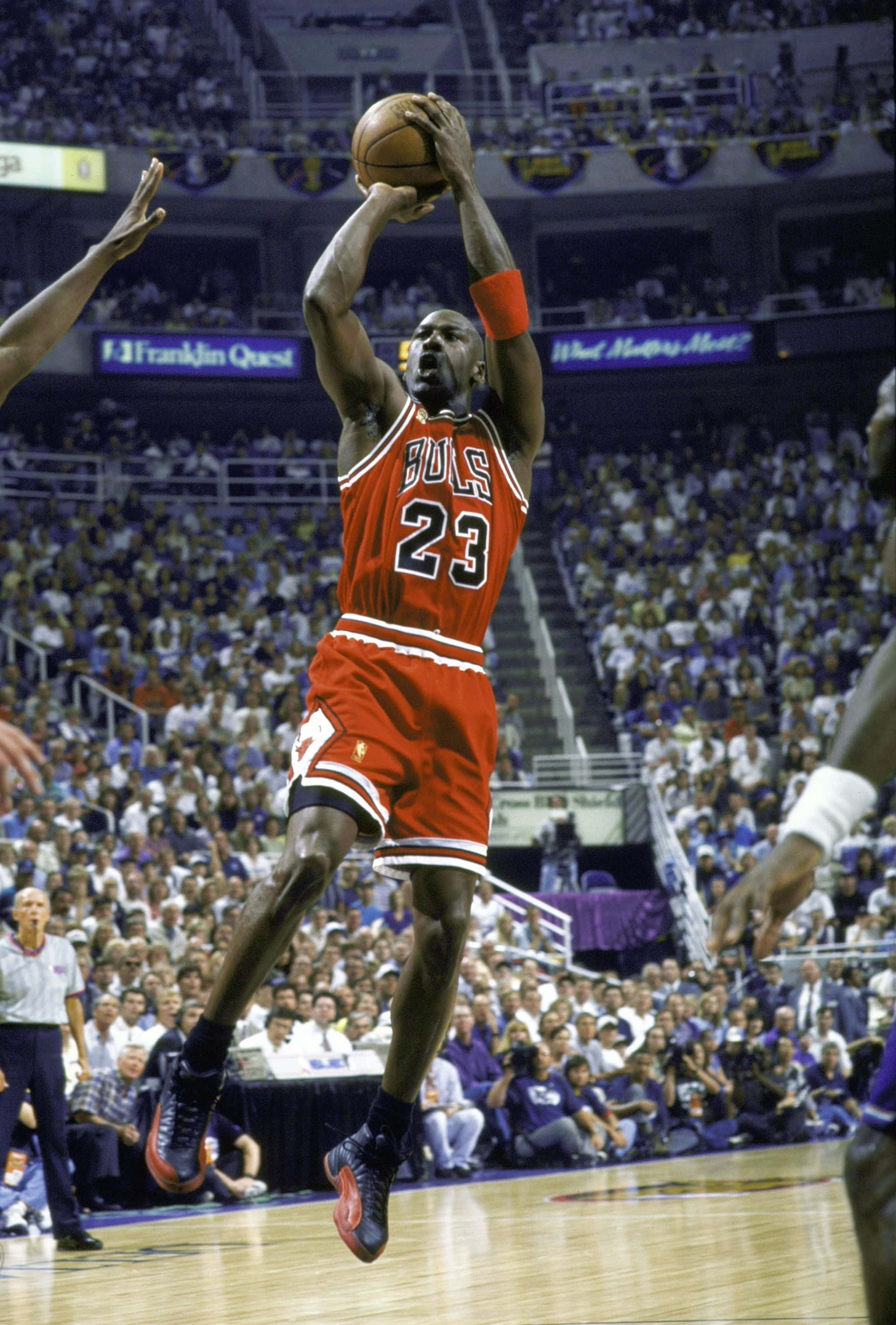 Jordan 桌布 壁紙 — 麥可喬丹穿著標誌性的紅色公牛隊球衣在球場上空翱翔，在座無虛席的NBA比賽中發起強力投籃。