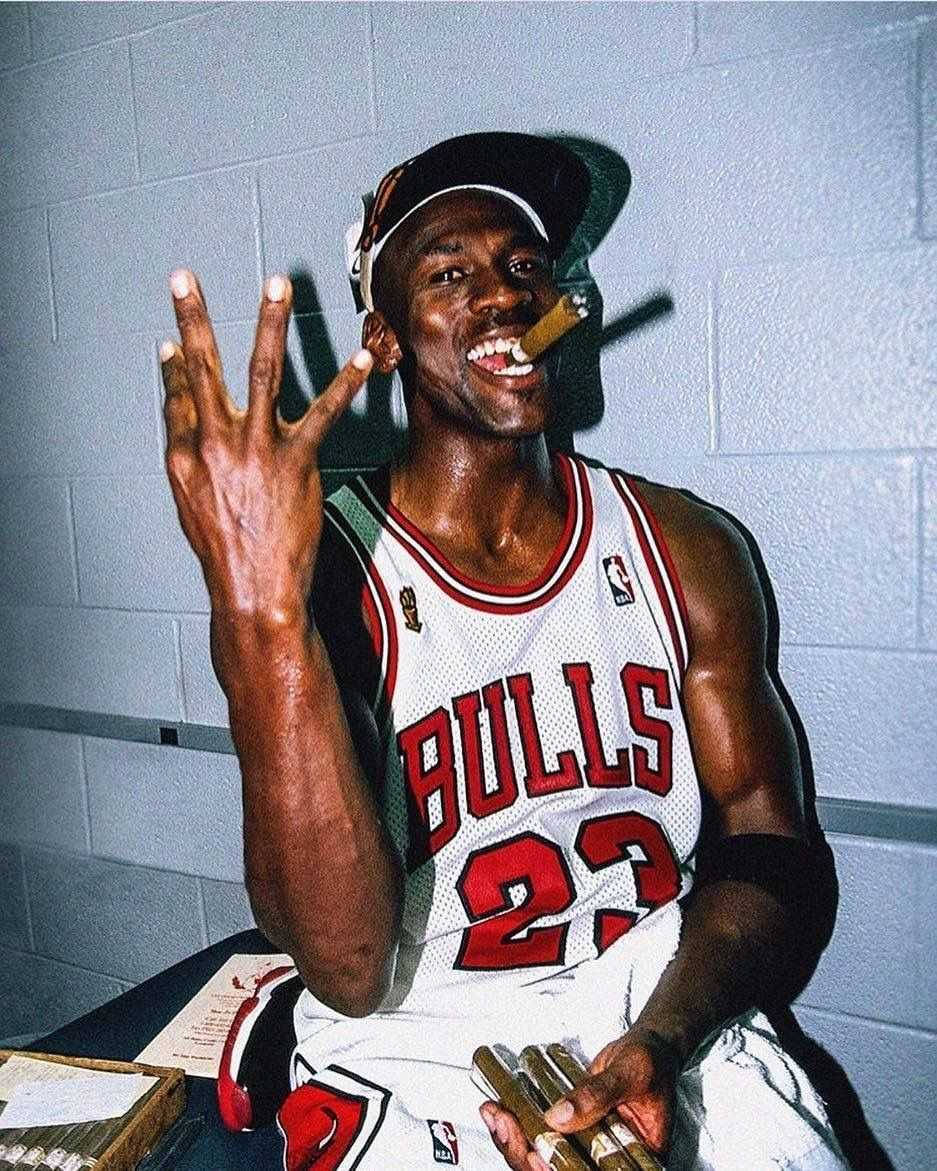 Chicago Bulls 桌布 壁紙 — 麥可喬丹身穿公牛隊球衣，在更衣室裡叼著雪茄微笑，舉起四根手指。