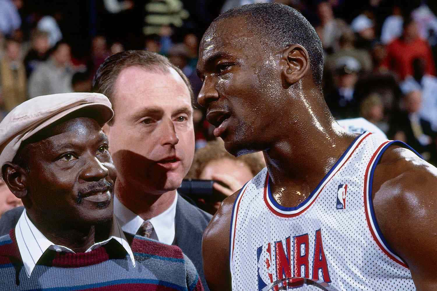 Jordan 桌布 壁紙 — 麥可喬丹身穿白色NBA球衣，在激烈的籃球比賽中與一名穿著條紋毛衣和帽子的男子對峙。