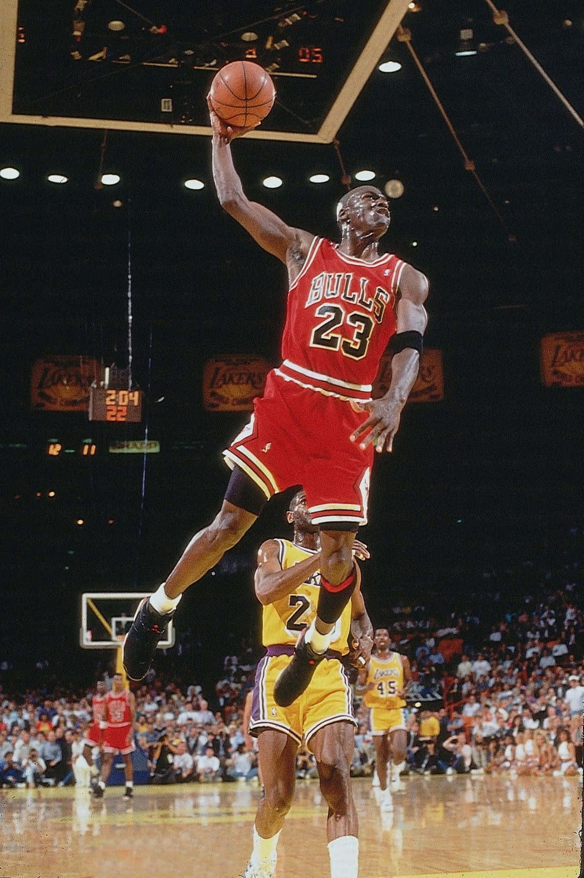 Dope Jordan 桌布 壁紙 — 麥可喬丹身穿紅色公牛球衣，在擠滿觀眾的NBA球場上飛越防守球員，完成致勝灌籃。