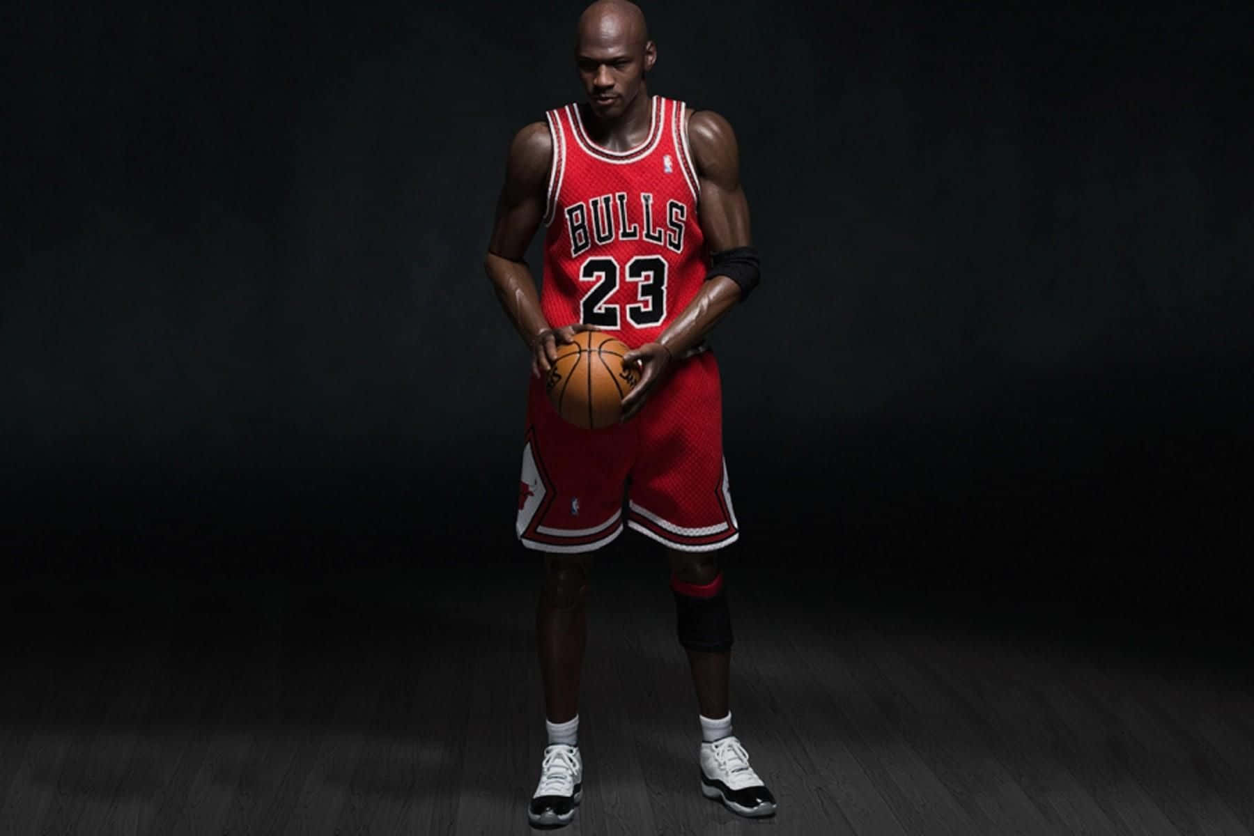 Jordan 桌布 壁紙 — 麥可喬丹身穿紅色公牛隊球衣，在深色攝影棚背景下手持籃球。