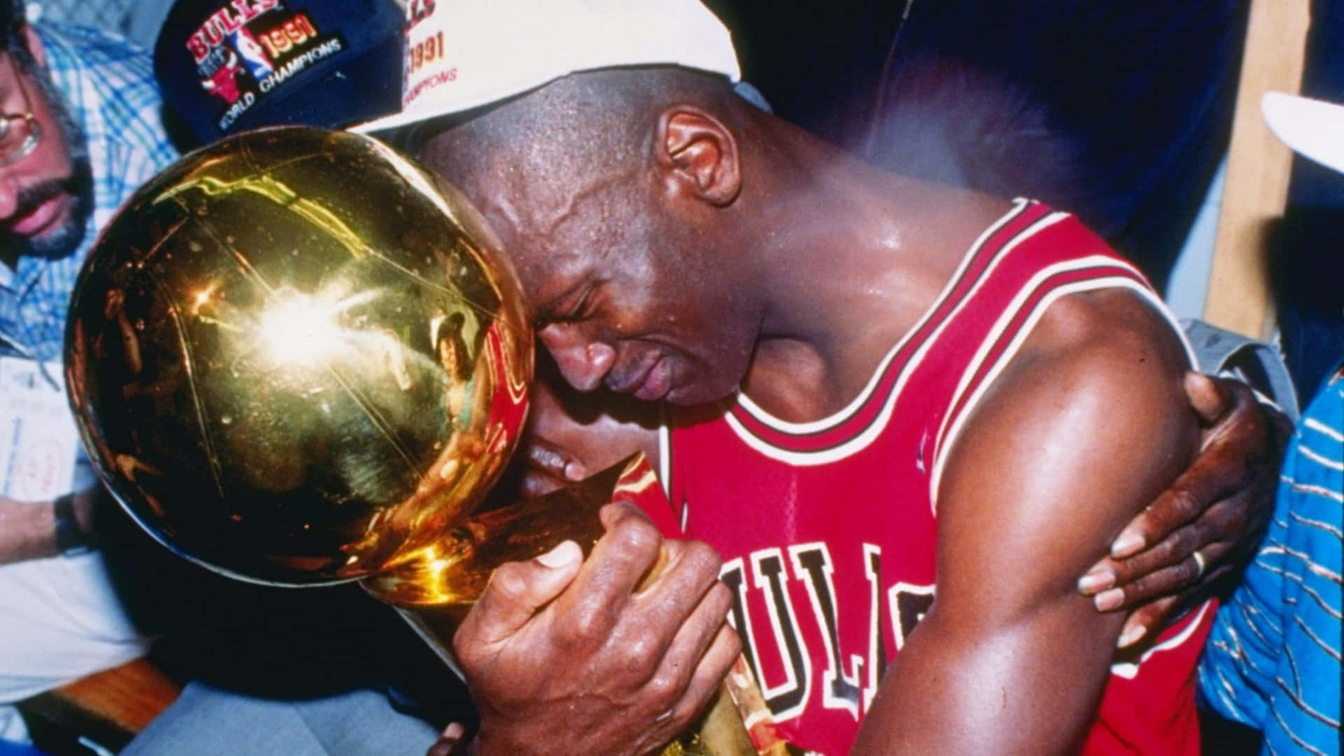 Jordan 桌布 壁紙 — 麥可喬丹身穿紅色公牛隊球衣，情感地親吻閃閃發光的金色NBA冠軍獎盃。