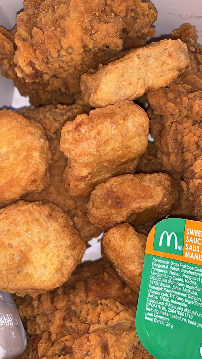 Chicken Nuggets 桌布 壁紙 — 麥當勞的酥脆金黃炸雞塊高高堆起，附帶一個綠色甜醬包。