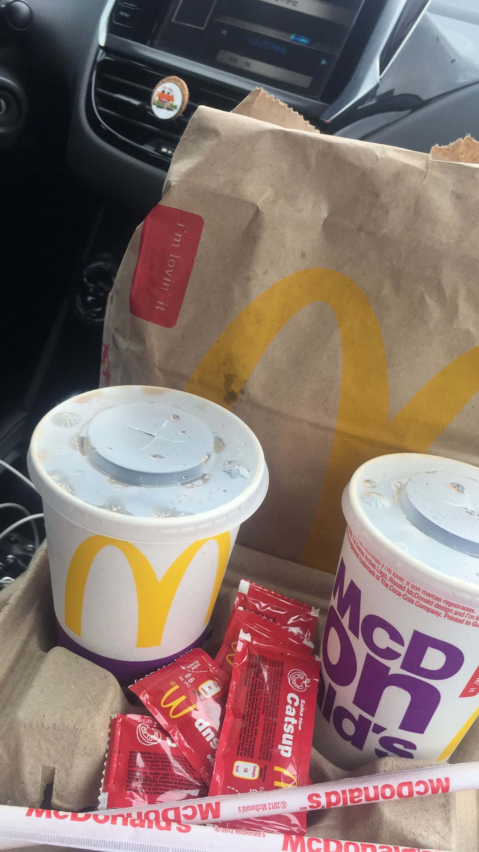 ketchup 桌布 壁紙 — 麥當勞薯條和飲品放在車內的紙板托盤上，儀表板清晰可見。