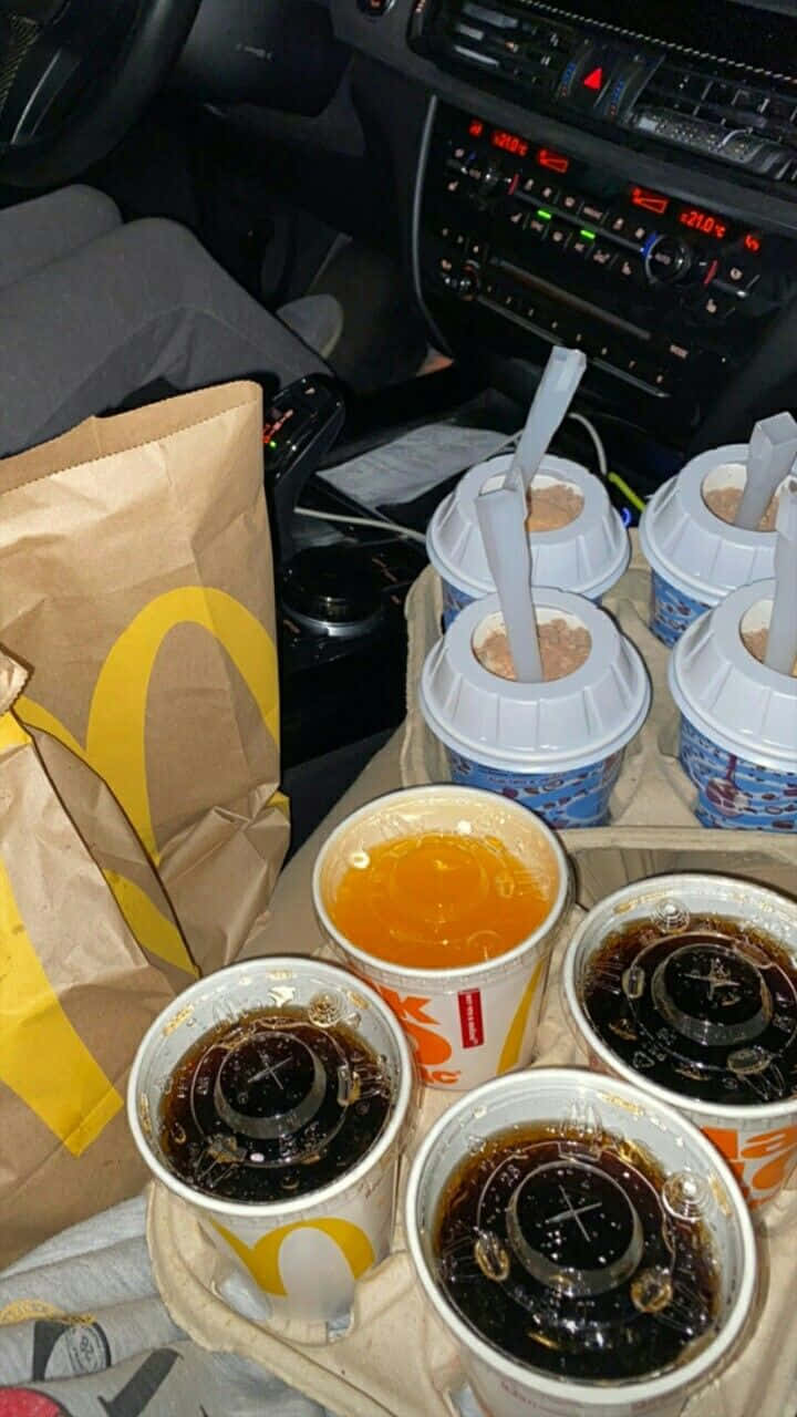 Soft Drink 桌布 壁紙 — 麥當勞飲料和食物袋在夜間堆疊在車內，儀表板燈光閃爍。