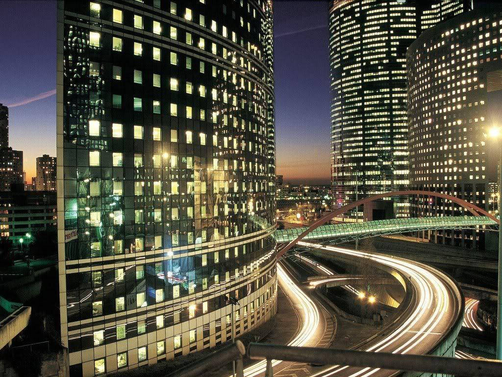 Buildings 桌布 壁紙 — 黃昏城市景觀，閃爍的摩天大樓和蜿蜒高架道路上汽車的光跡。