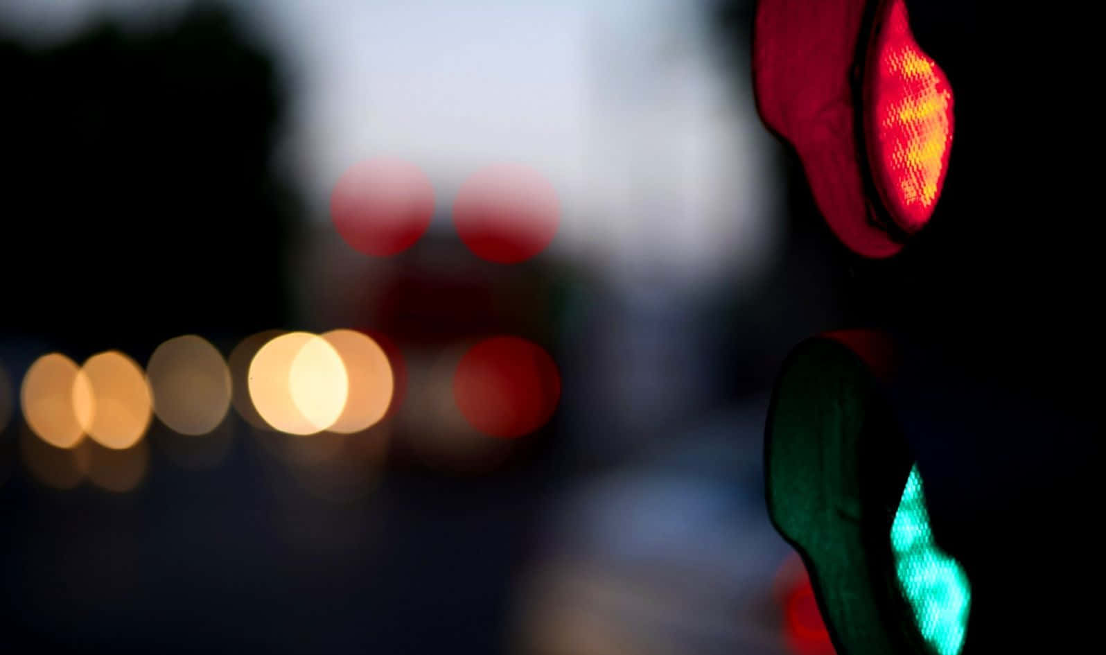 Stop Light 桌布 壁紙 — 黃昏時交通燈亮起紅燈的特寫，背景中模糊的城市燈光柔和地閃爍。