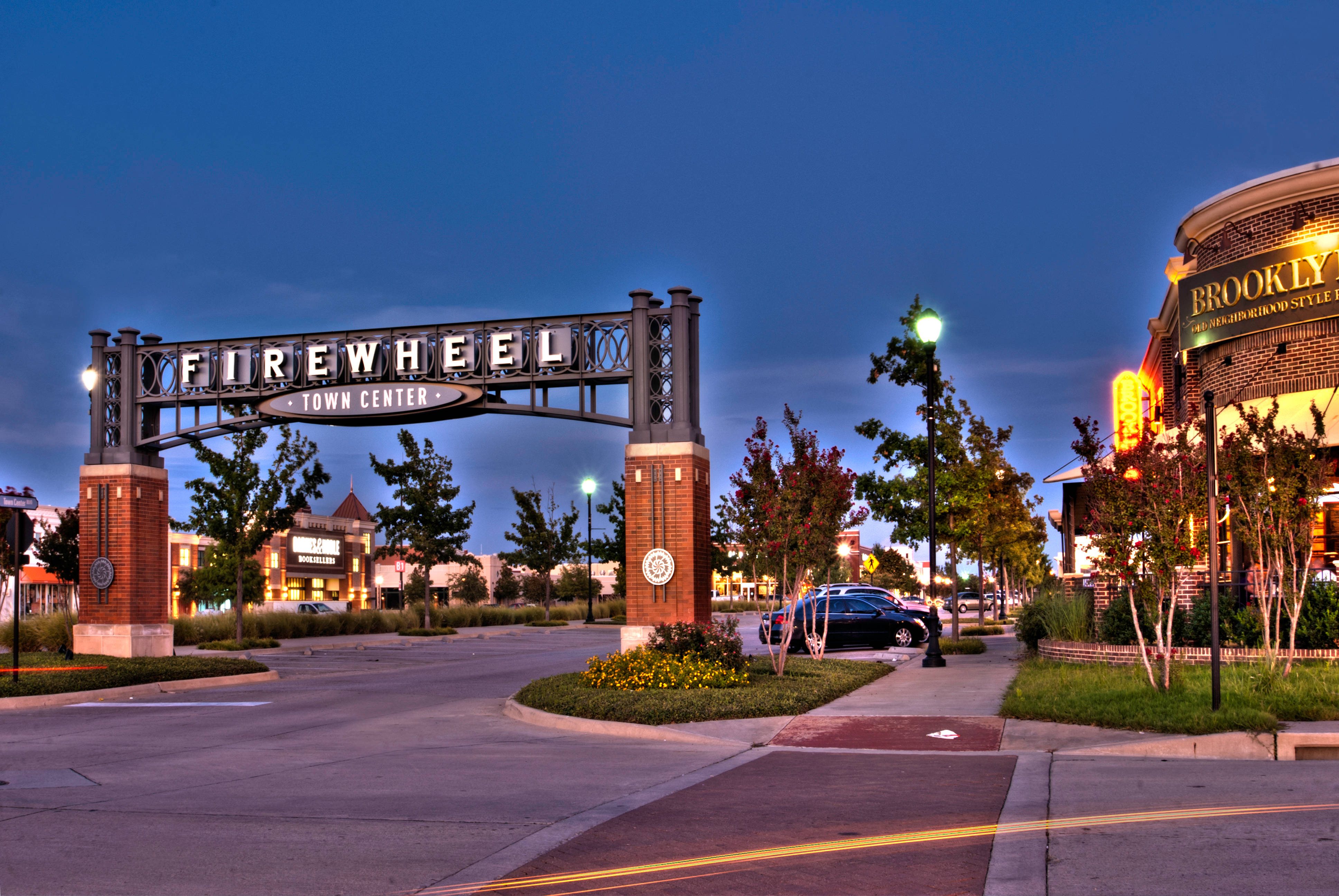 夜空 桌布 壁紙 — 黃昏時分，Firewheel Town Center 燈光璀璨的拱門，磚柱和發光的街燈。