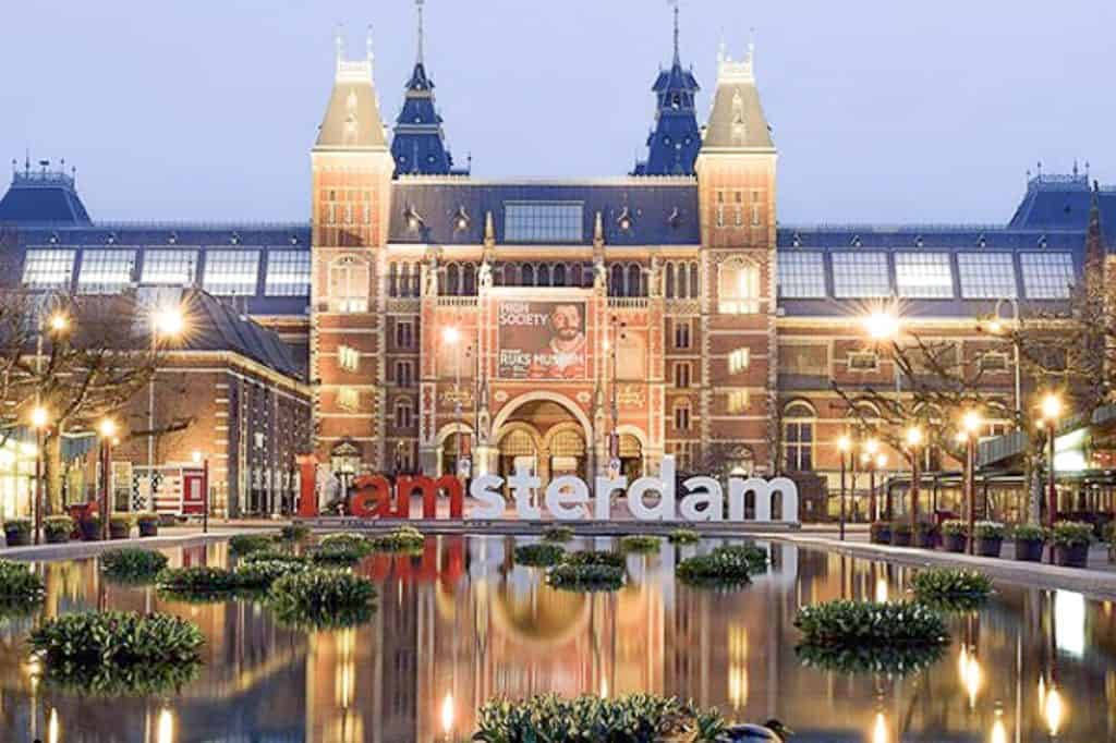 Museum 桌布 壁紙 — 黃昏時分，I amsterdam 標誌在宏偉的國立博物館前溫暖發光，水中倒影閃爍。