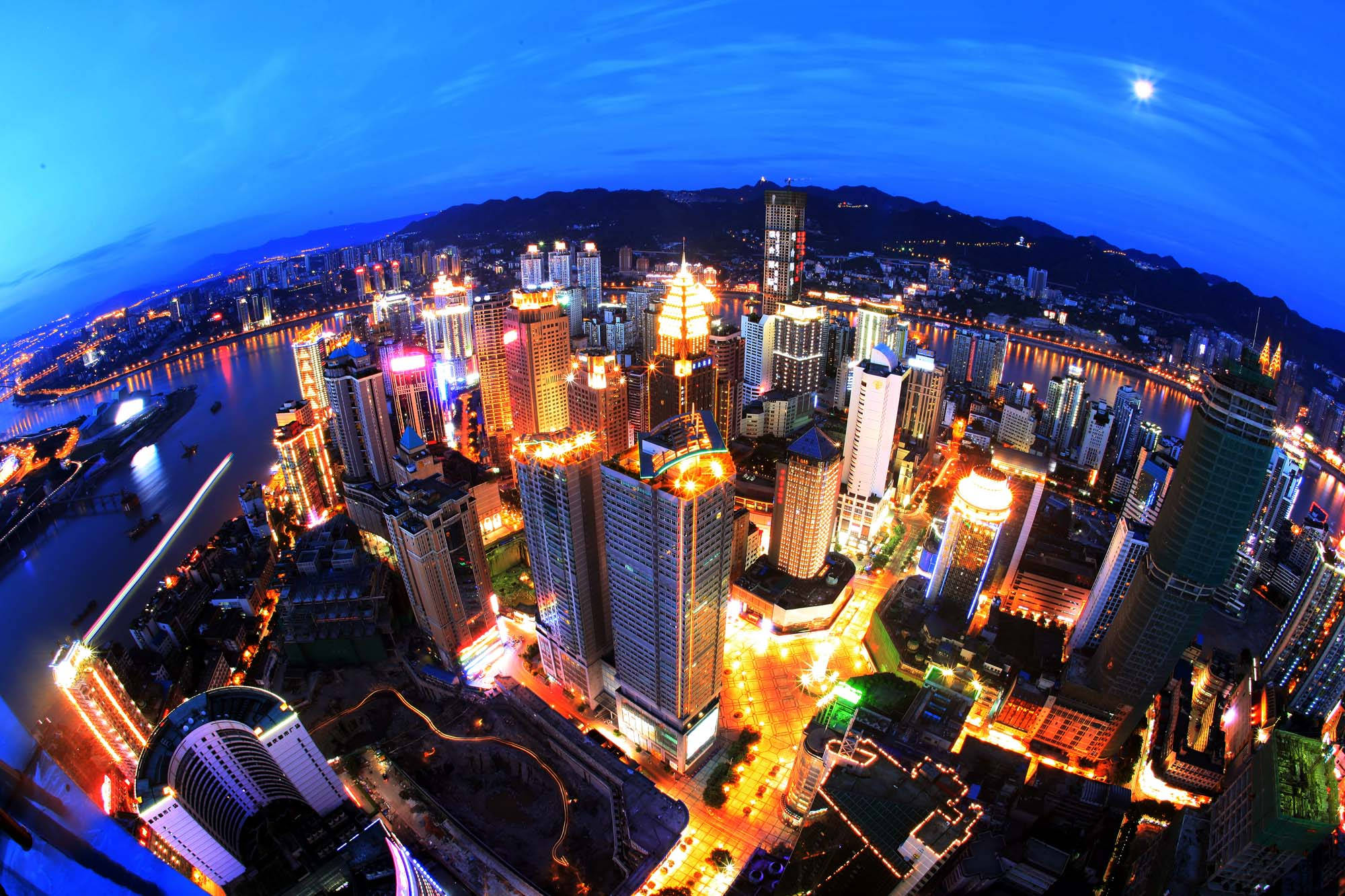 Chongqing 桌布 壁紙 — 黃昏時分，一個充滿活力的魚眼視角，展現廣闊的城市天際線，閃爍的摩天大樓和河流在深藍色天空下反射霓虹燈光。