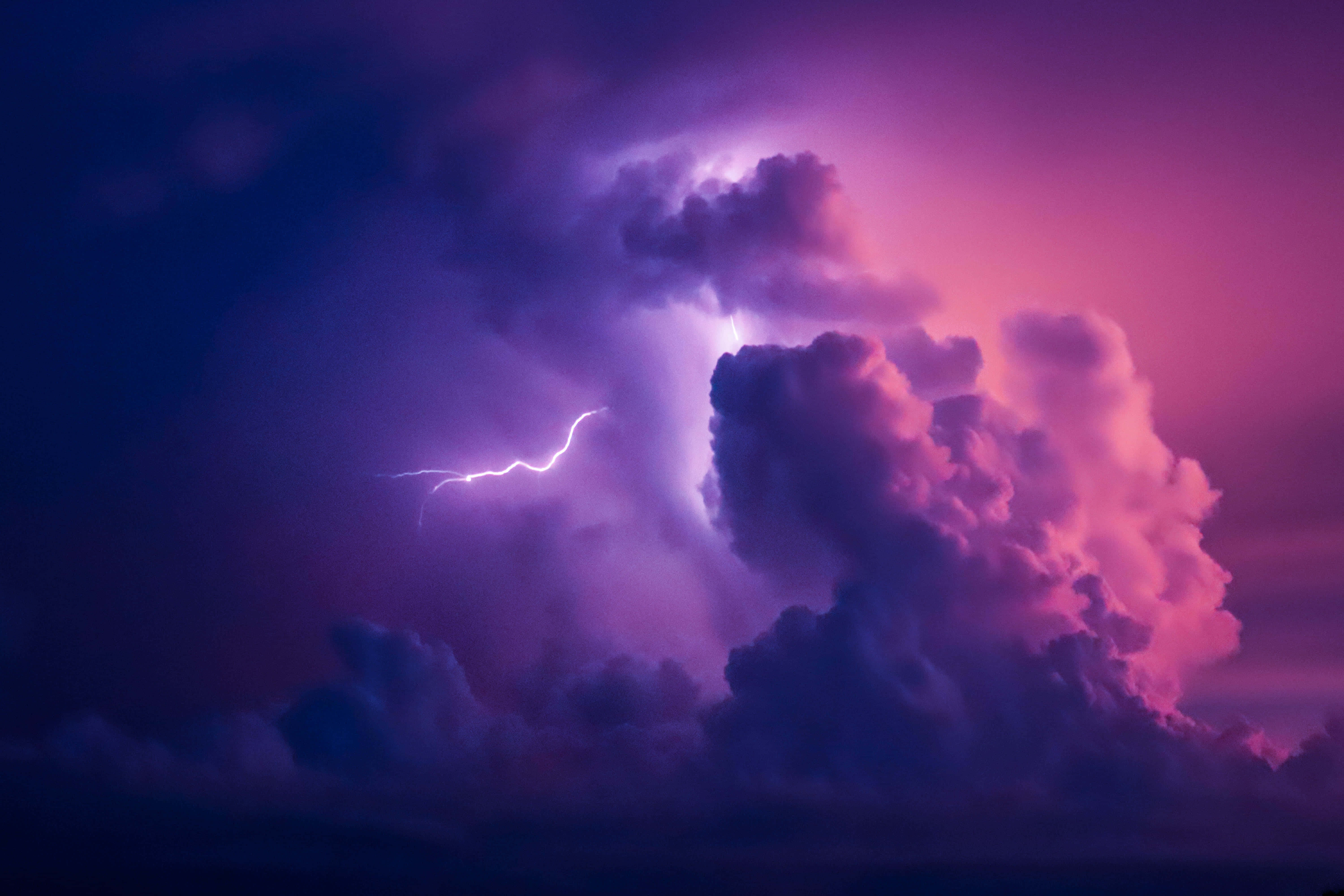 Aesthetic Night Sky 桌布 壁紙 — 黃昏時分，一場戲劇性的紫色和粉紅色雷暴，伴隨著明亮的閃電劈開高聳的雲層。