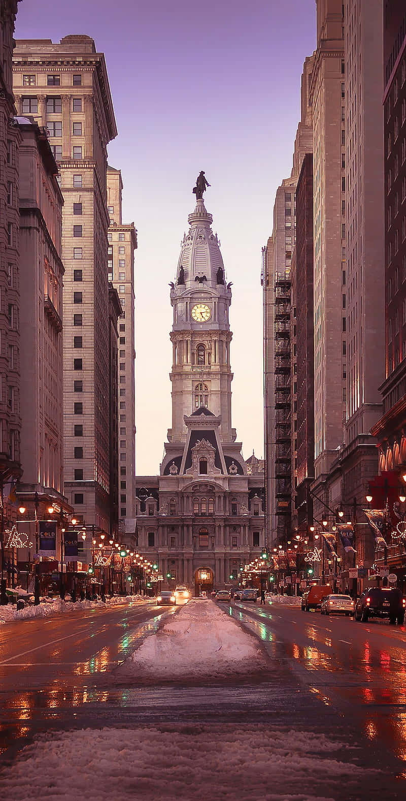 Philly 桌布 壁紙 — 黃昏時分，一座宏偉的鐘樓聳立在積雪的城市街道之上，潮濕的人行道反射著溫暖的路燈光。