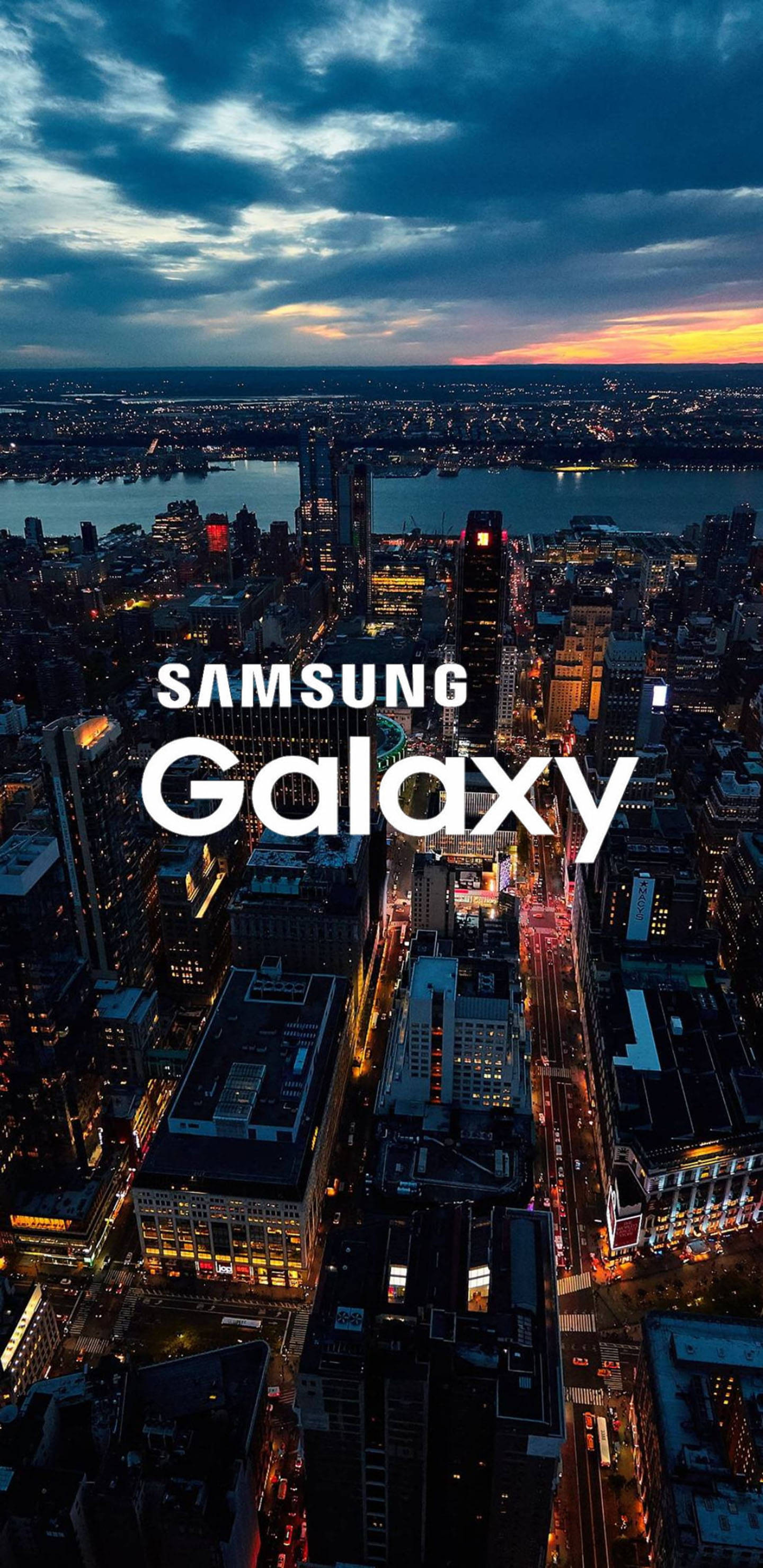 三星 桌布 壁紙 — 黃昏時分，一座廣闊城市的鳥瞰圖，閃爍的摩天大樓和充滿活力的日落地平線。