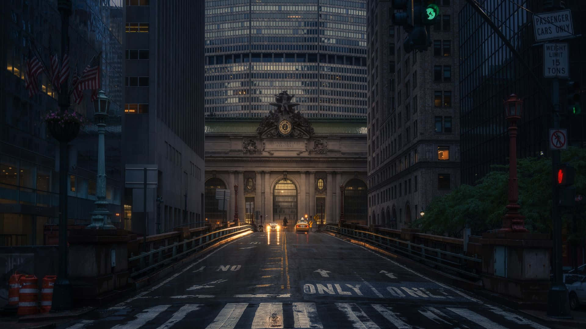 New York 桌布 壁紙 — 黃昏時分，一條濕漉漉的城市街道通往宏偉的布雜藝術風格中央車站，四周環繞著高聳的摩天大樓。