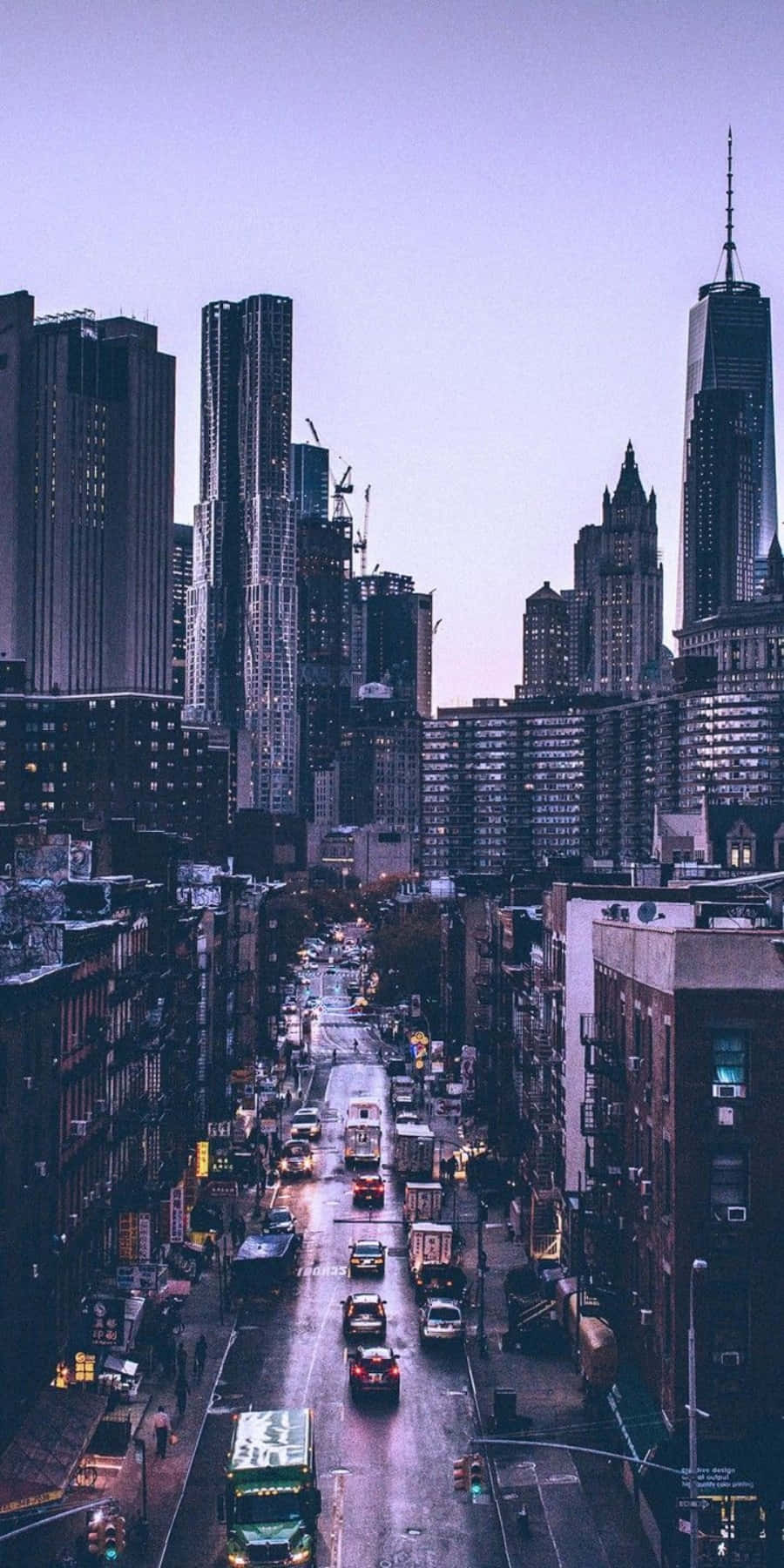Nyc Aesthetic 桌布 壁紙 — 黃昏時分，一條被雨水浸濕的城市街道，高聳的摩天大樓和閃爍的車頭燈伸向遠方。