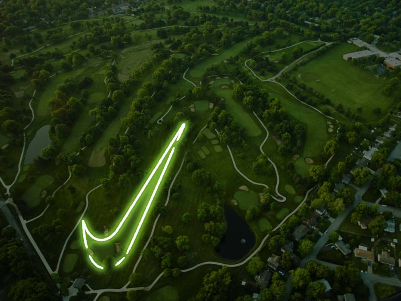 Nike 桌布 壁紙 — 黃昏時分，在高爾夫球場上雕刻出發光的綠色Nike勾號的鳥瞰圖。