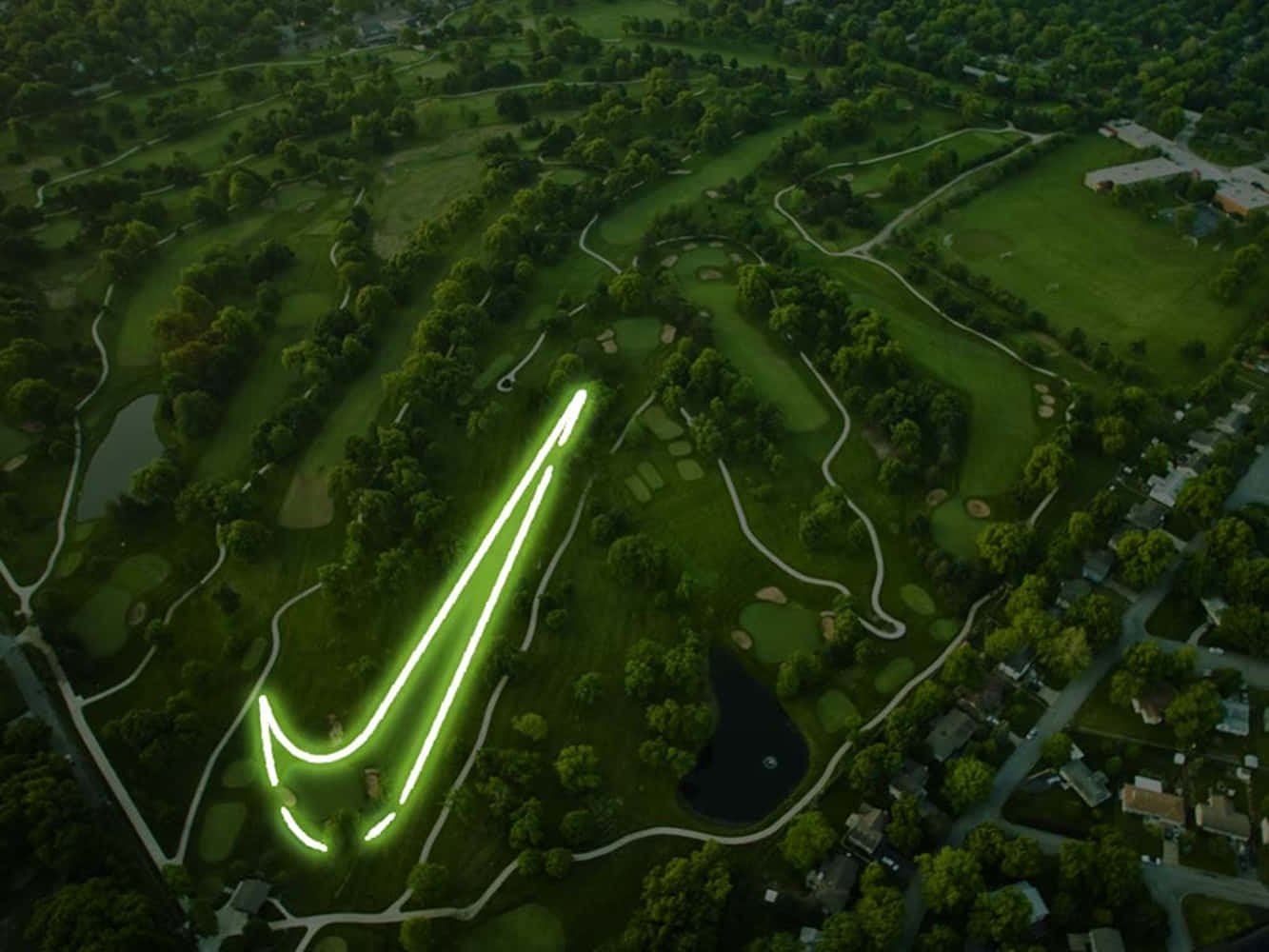 Awesome Golf 桌布 壁紙 — 黃昏時分，在高爾夫球場上雕刻出發光的綠色Nike勾號的鳥瞰圖。