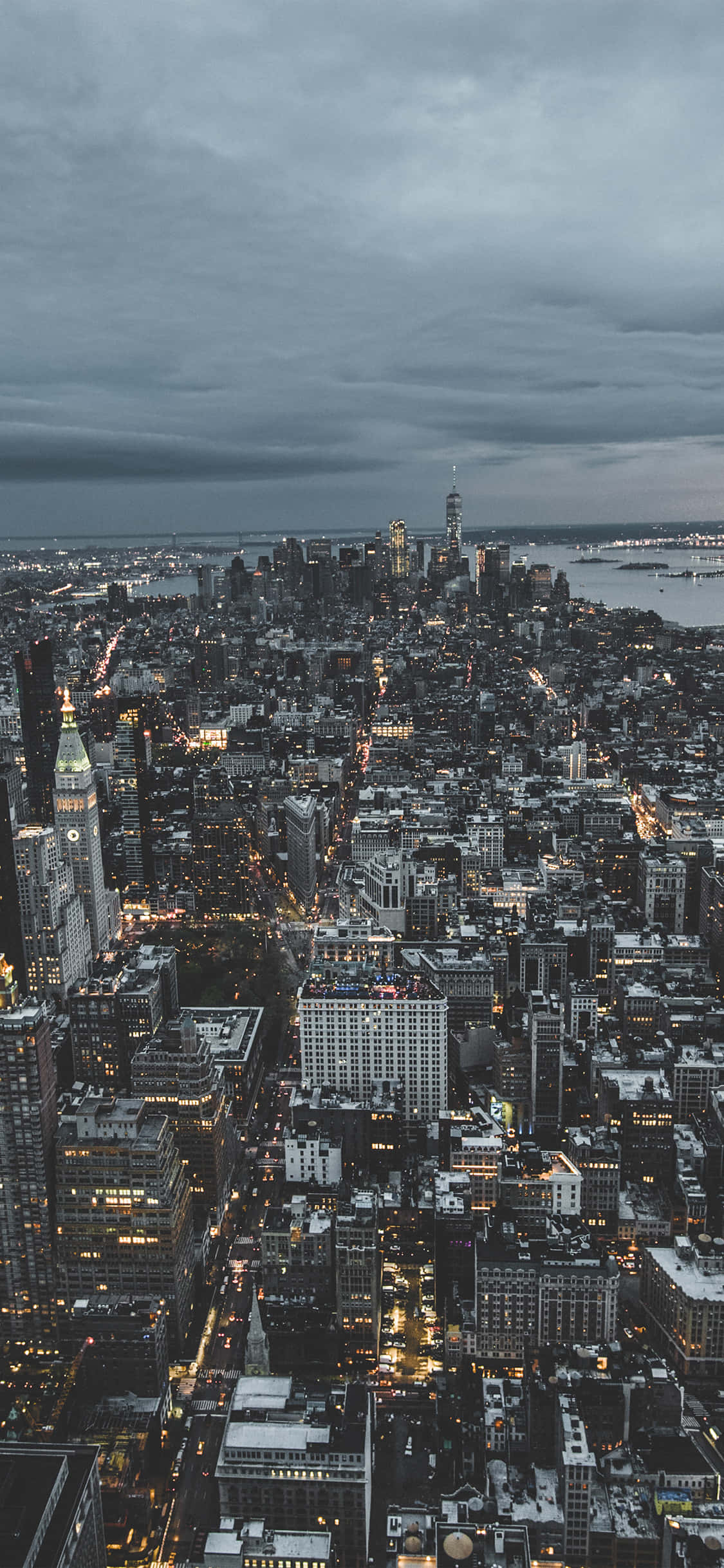 New York 桌布 壁紙 — 黃昏時分，多雲天空下，雪景城市景觀的鳥瞰圖，閃爍的路燈和摩天大樓。