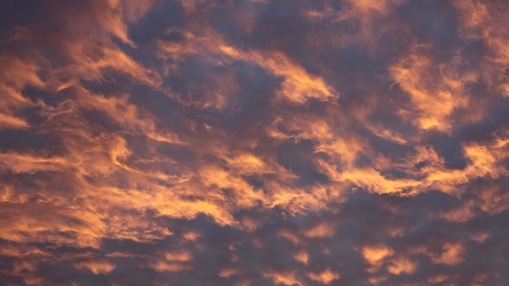 Clouds Aesthetics 桌布 壁紙 — 黃昏時分，天空充滿了火橙色和深紫色的雲彩，場面壯觀。