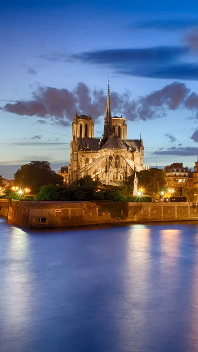 Notre Dame 桌布 壁紙 — 黃昏時分，巴黎聖母院在燈光映照下，倒映在塞納河中，天空籠罩著憂鬱的暮色。