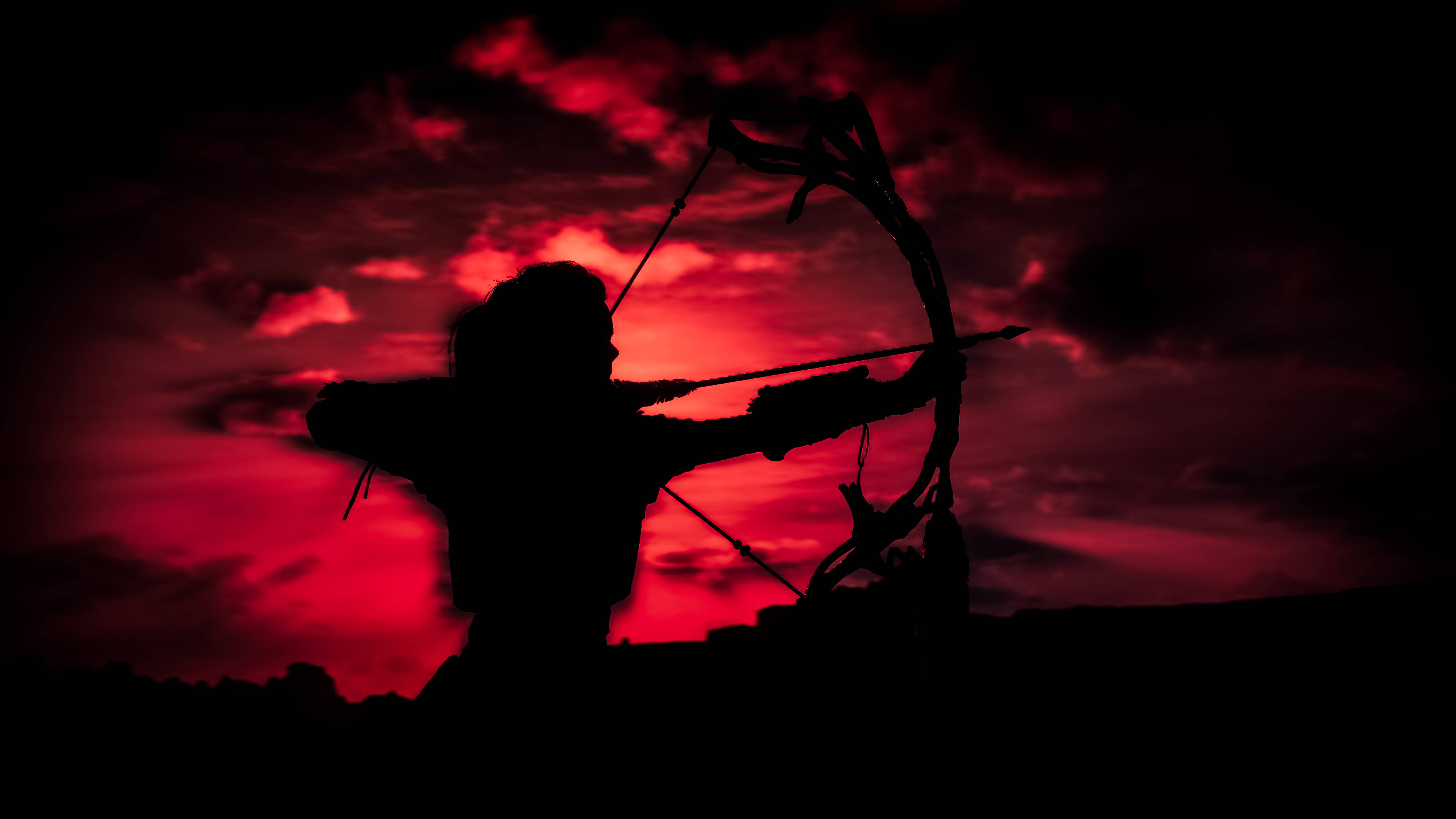 Archery 桌布 壁紙 — 黃昏時分，戰士拉弓的剪影映襯著戲劇性的紅色天空。
