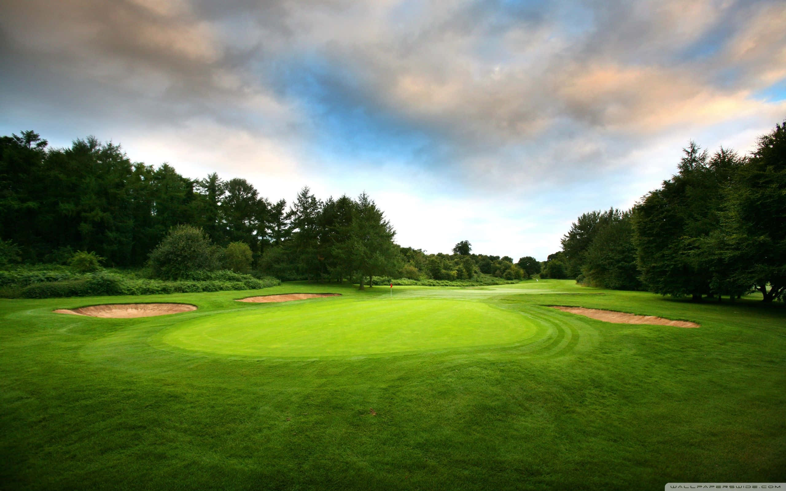 Pixel 3 Golf Course 桌布 壁紙 — 黃昏時分，戲劇性的多雲天空下，一個寧靜的高爾夫球場，擁有充滿活力的綠色球道和沙坑。