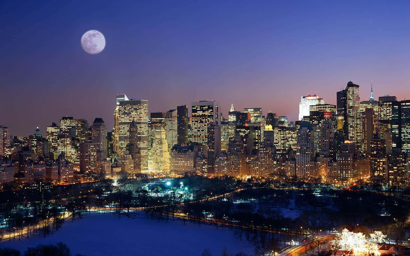 New York 桌布 壁紙 — 黃昏時分，白雪覆蓋的中央公園，滿月懸掛在閃爍的曼哈頓天際線之上。