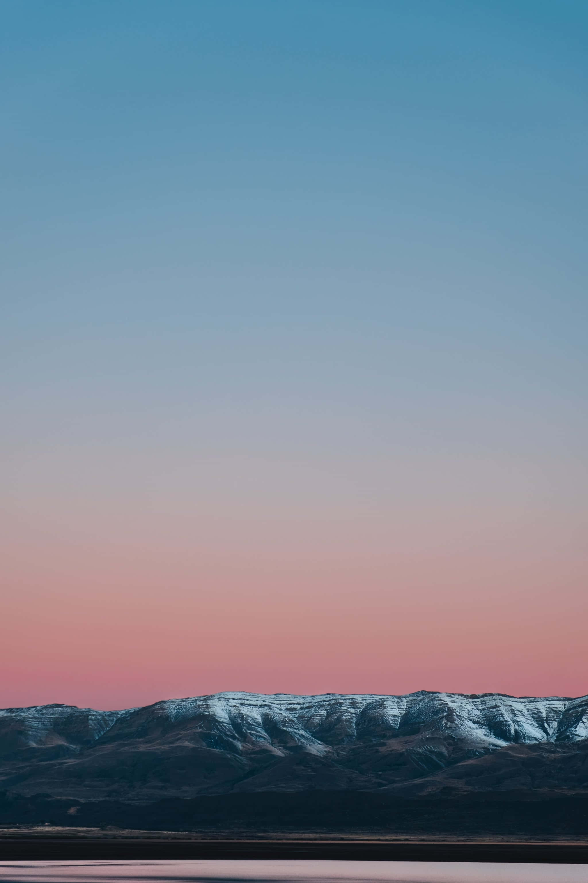 山景 桌布 壁紙 — 黃昏時分，白雪覆蓋的山峰在藍粉漸變的天空中形成剪影。