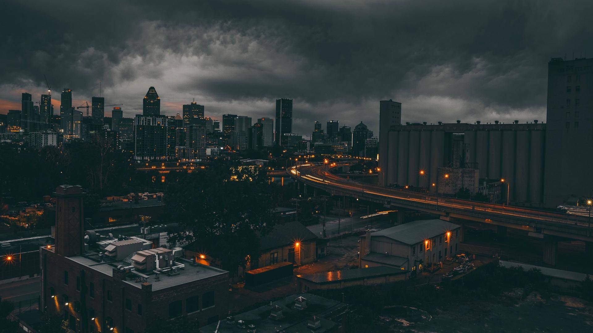 Montreal 桌布 壁紙 — 黃昏時分，陰鬱的城市天際線，閃爍的路燈和頭頂上籠罩的黑暗風暴雲。