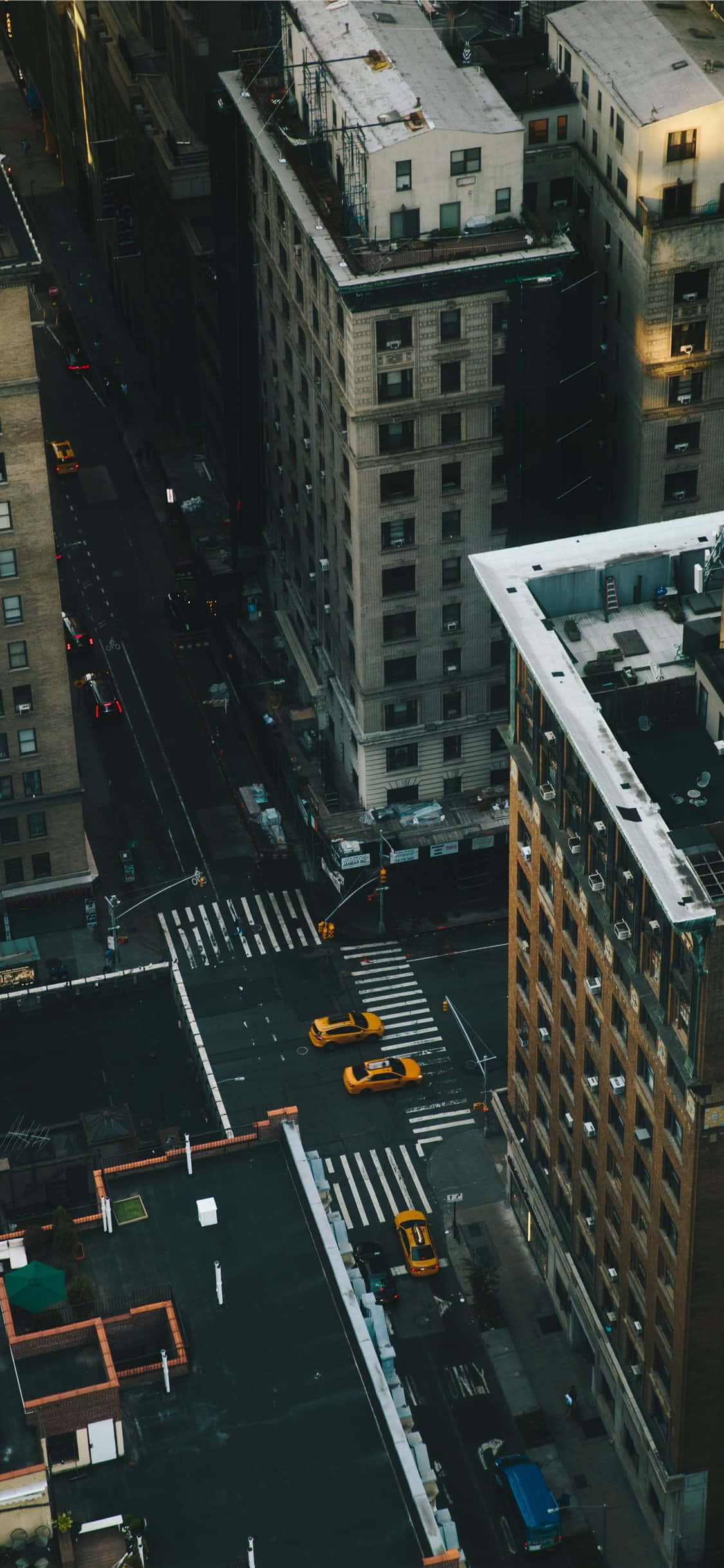 New York 桌布 壁紙 — 黃昏時分，雨中的城市街道上空鳥瞰，黃色的士在高樓大廈之間穿梭。